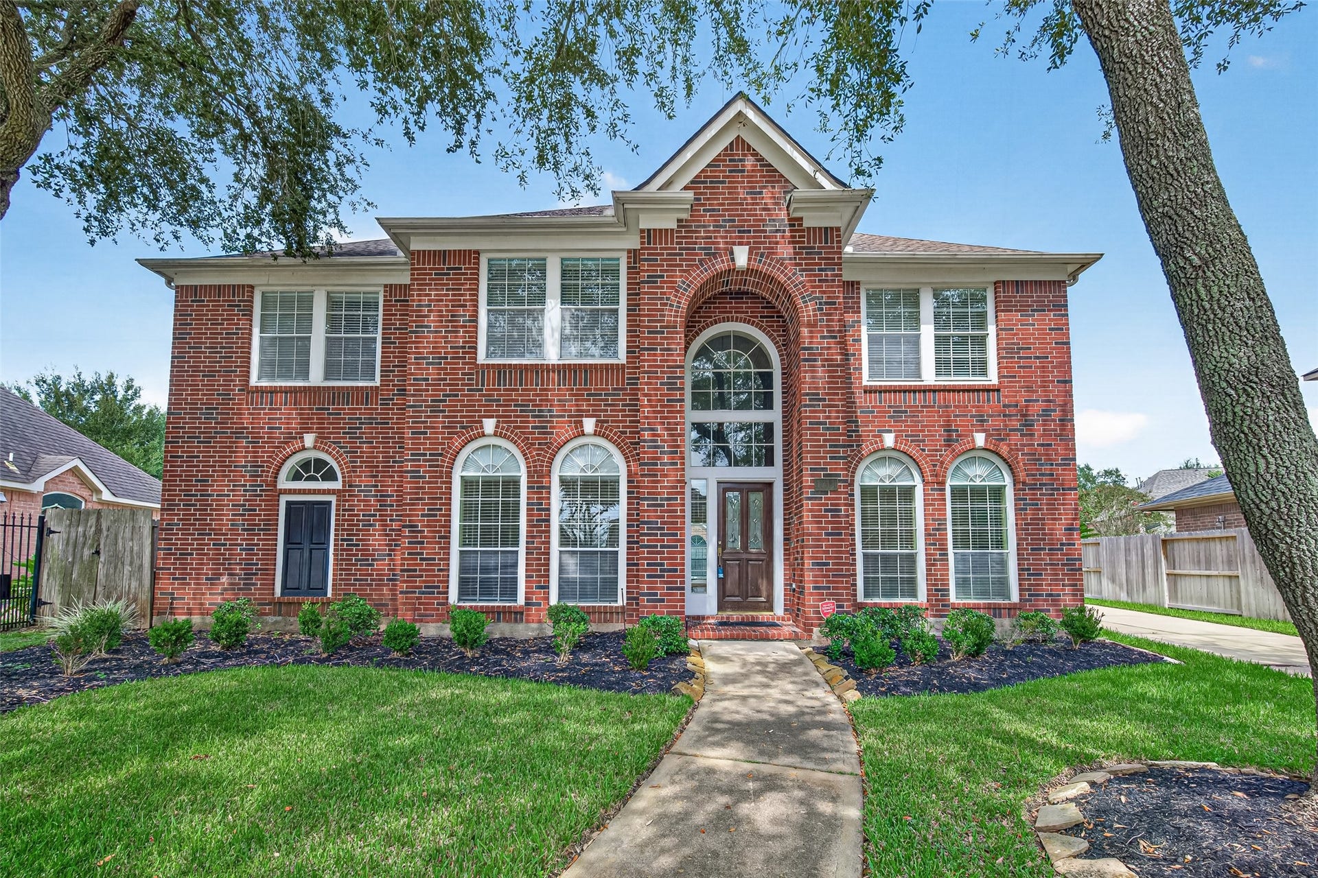 1711 Emma Cove Court, Sugar Land, TX 77479 Striking two-story brick exterior framed by mature shade trees and manicured landscaping.
