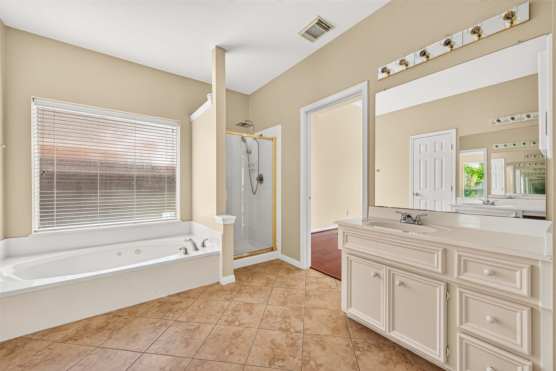 1711 Emma Cove Court, Sugar Land, TX 77479 Relaxing jetted tub sits beneath a large window, accompanied by a separate glass-enclosed shower and additional vanity.