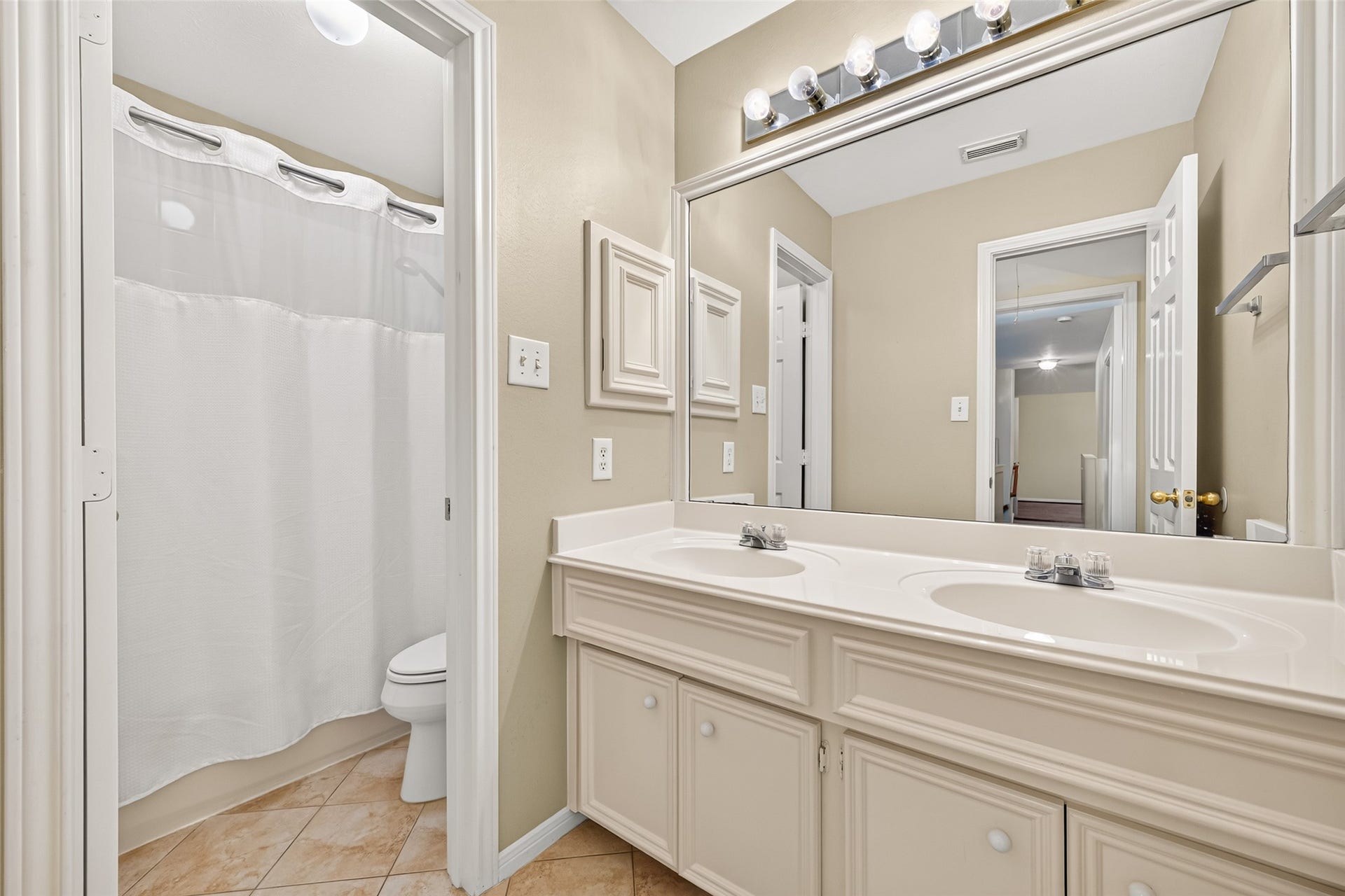 1711 Emma Cove Court, Sugar Land, TX 77479 Secondary bathroom is arranged with a double-sink vanity, oversized mirror, and a separate tub and toilet area.