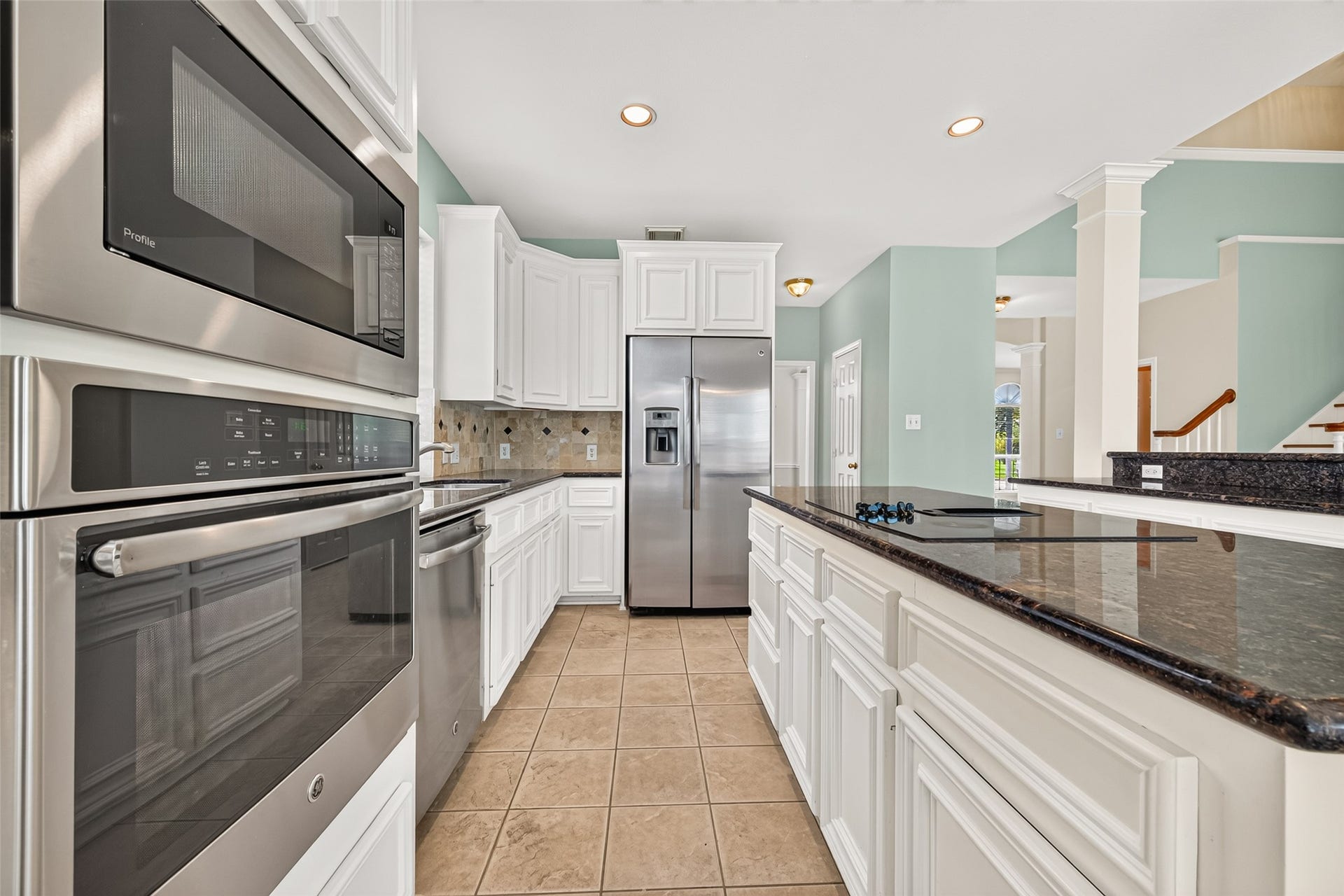 1711 Emma Cove Court, Sugar Land, TX 77479 Bright kitchen showcases white cabinetry, granite countertops, a center island with cooktop, recessed lighting, and stainless steel appliances.