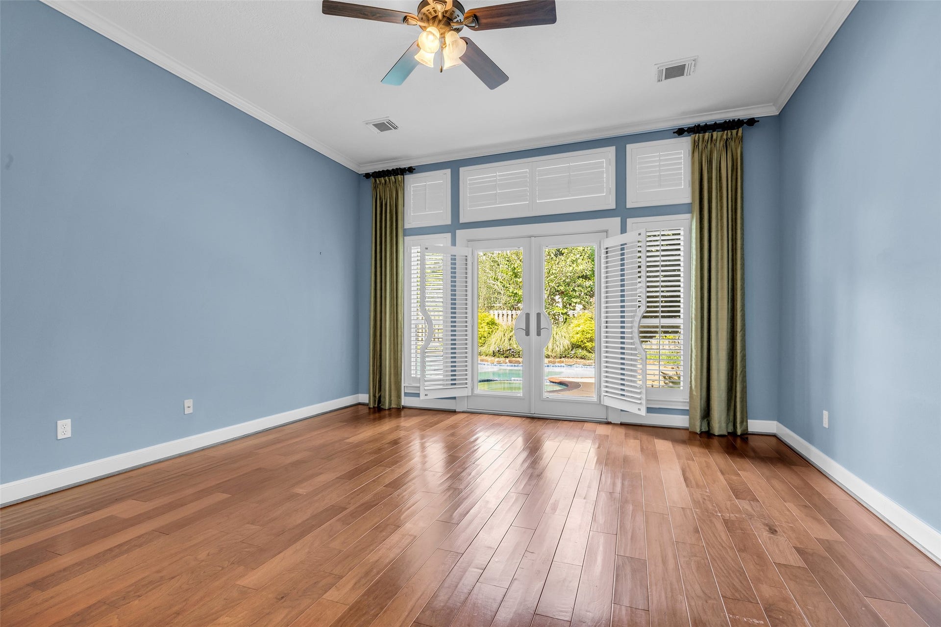 5907 Rocky Brook Drive, Houston, TX 77345 Spacious first-floor primary bedroom with hardwood floors, high ceilings, and French doors overlooking the private pool.