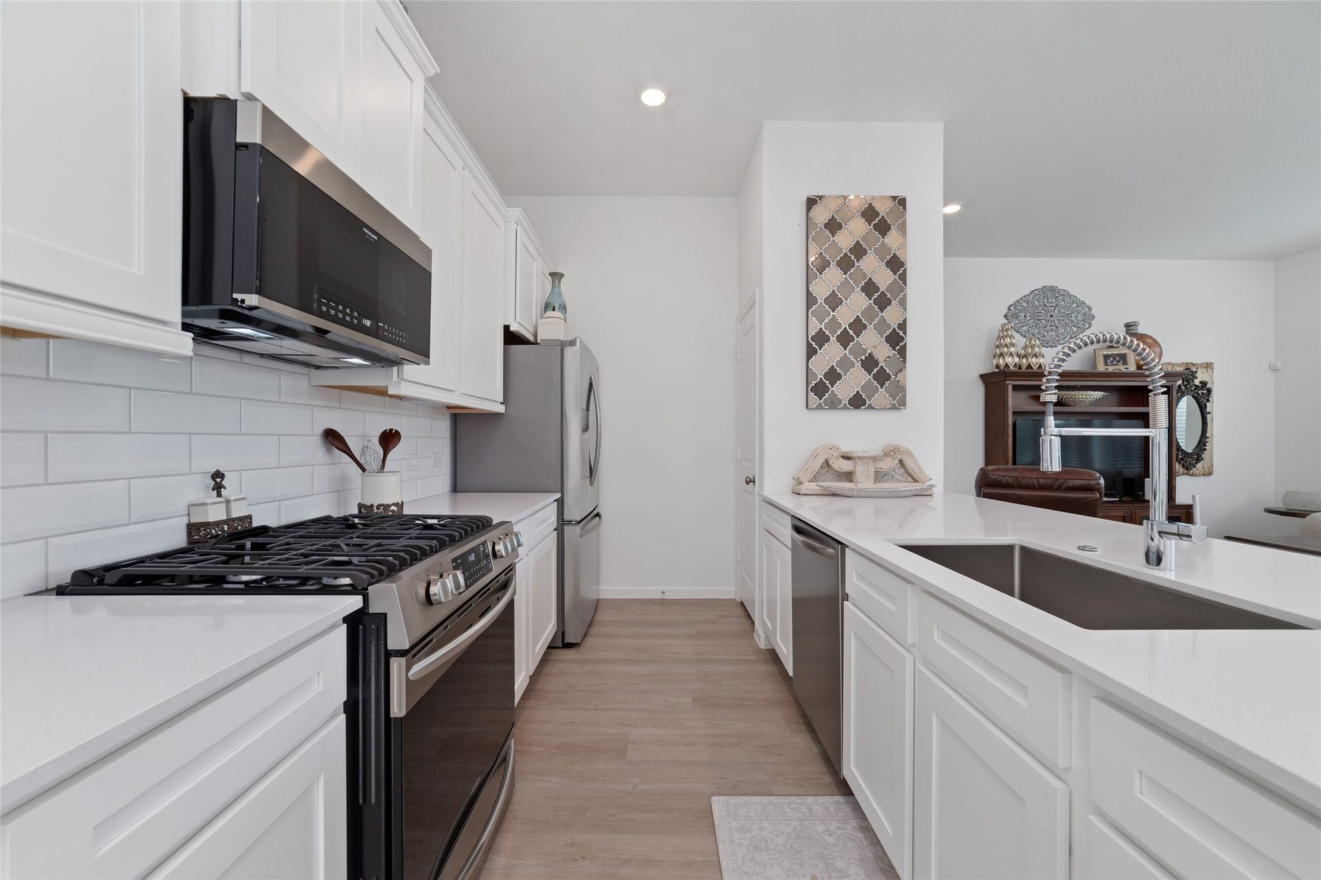 5715 Foggy Vine Court, Fulshear, TX 77441 The kitchen features crisp white cabinetry, a gas range, built-in microwave, dishwasher, generous counter space, and a functional layout for meal preparation.