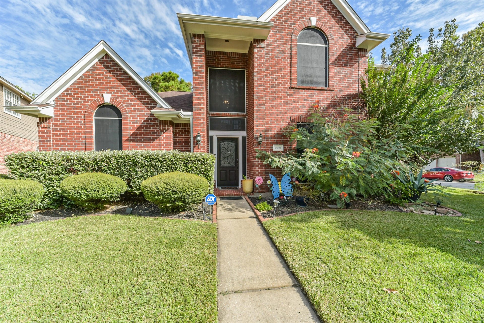 18402 Spinner Court Drive, Humble, TX 77346 A two-story covered porch surrounded by lush, verdant landscaping.