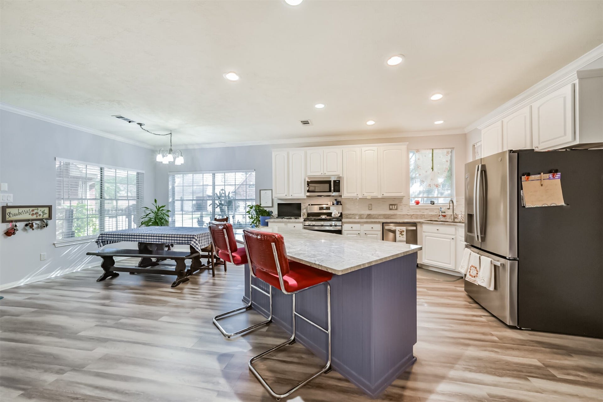 18402 Spinner Court Drive, Humble, TX 77346 A center island anchors the kitchen, complemented by a sunlit breakfast room with two corner windows. Crown molding, tall cabinets, and stainless steel appliances complete the space.