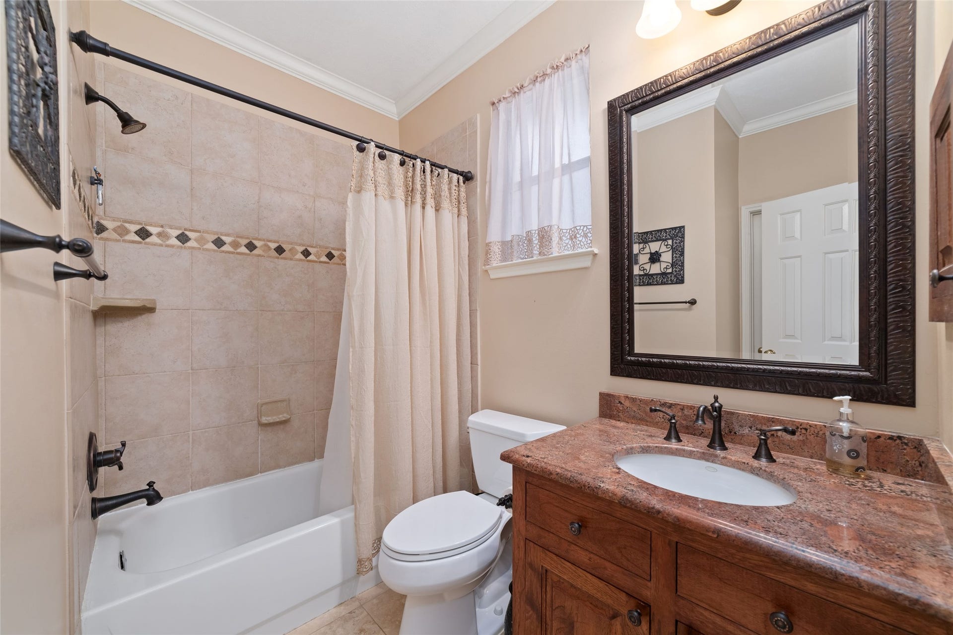 First-floor secondary bathroom with tub-and-shower combination, tile surround, and furniture-style vanity.
