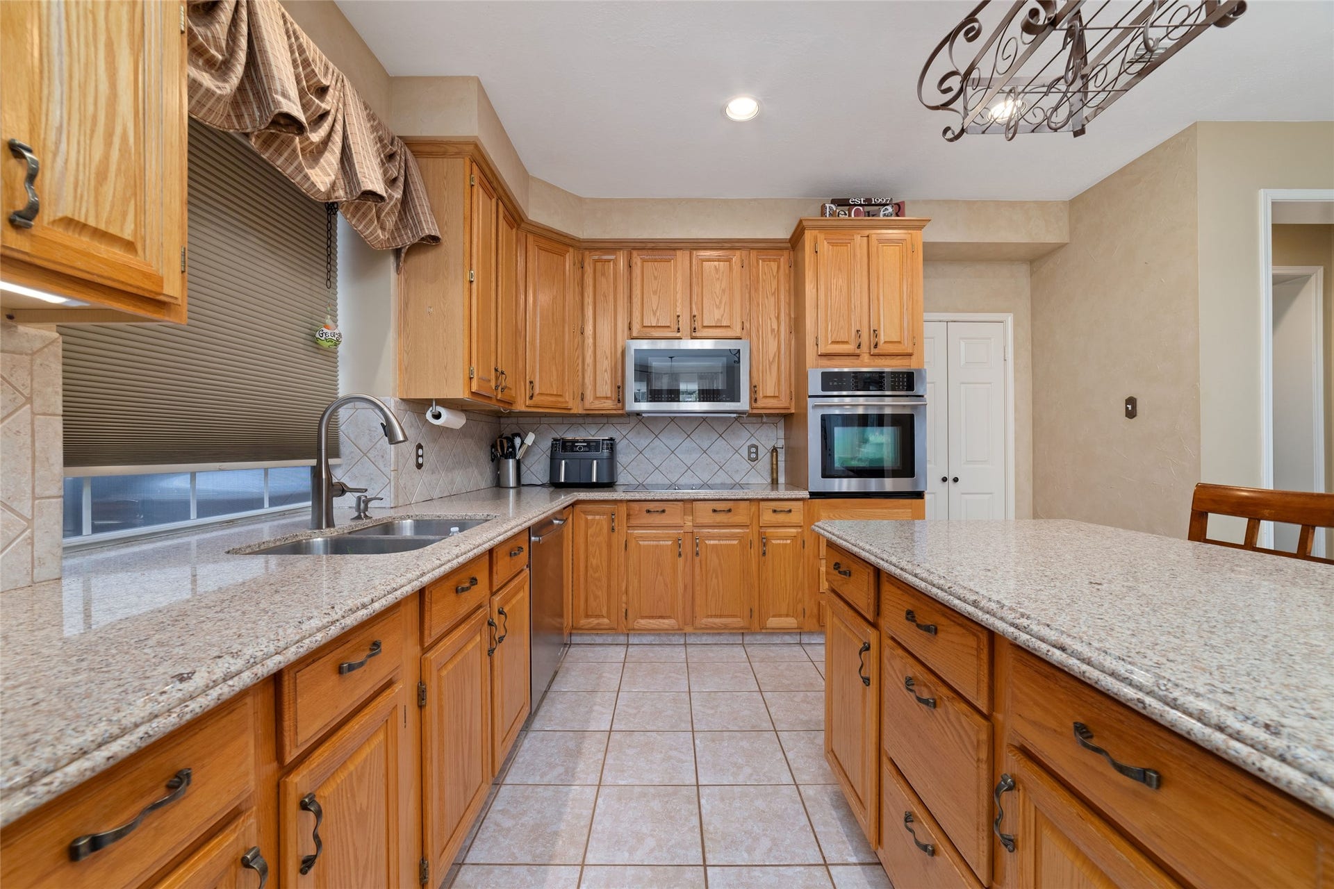 Galley view of the kitchen highlighting generous counter space, extensive cabinetry, recessed lighting, and stainless steel appliances.