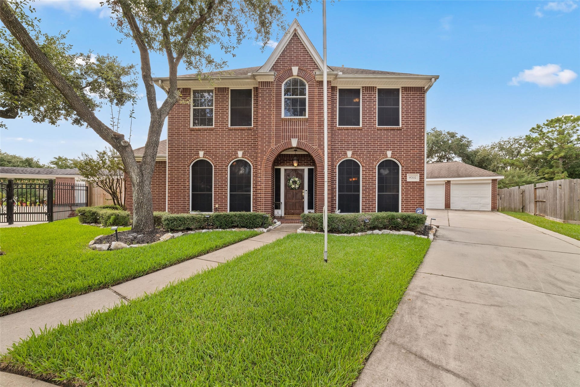 Welcoming front elevation with arched architectural details, established landscaping, and a broad driveway.