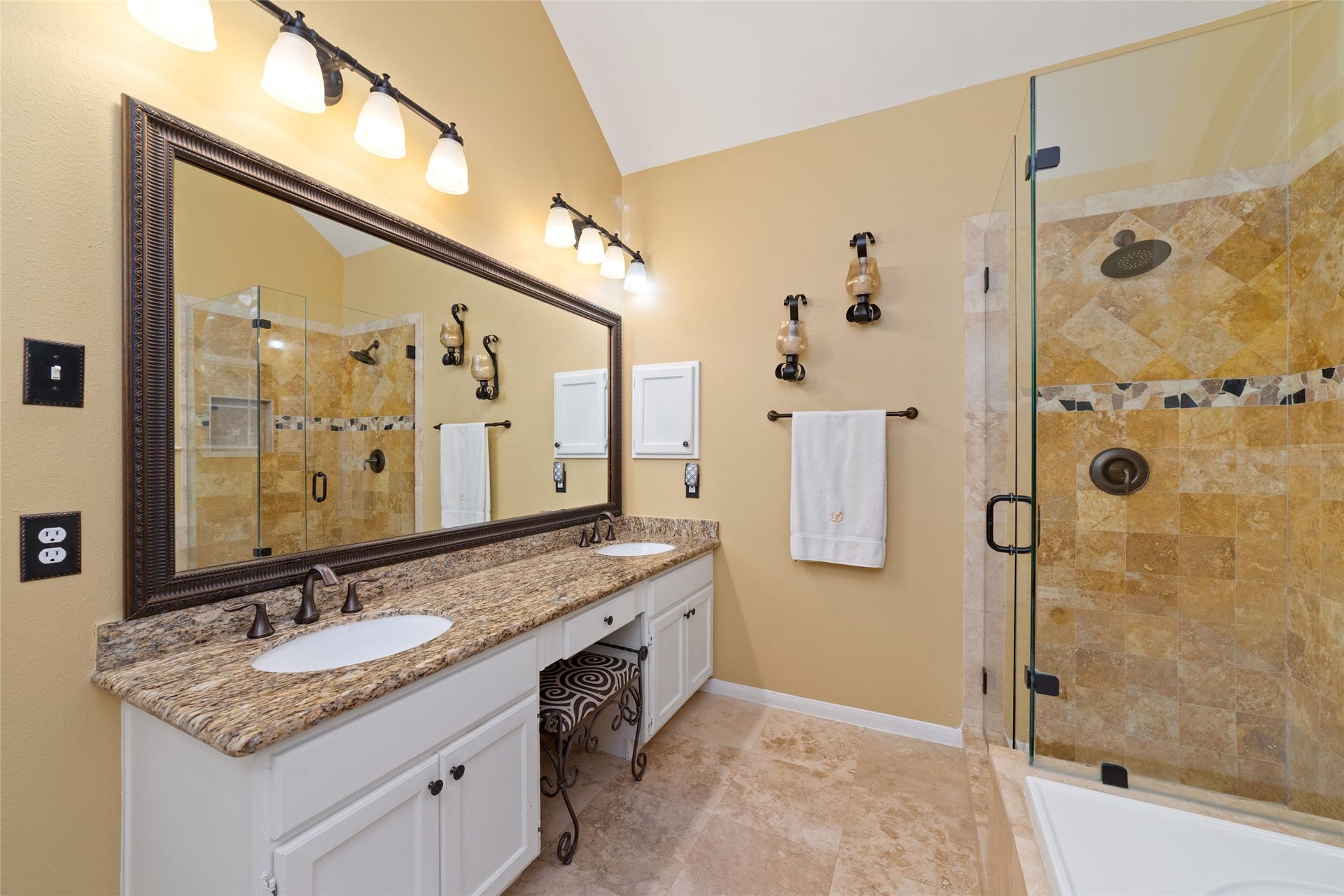 Extended primary vanity with dual sinks and a spacious separate shower finished with decorative tile.