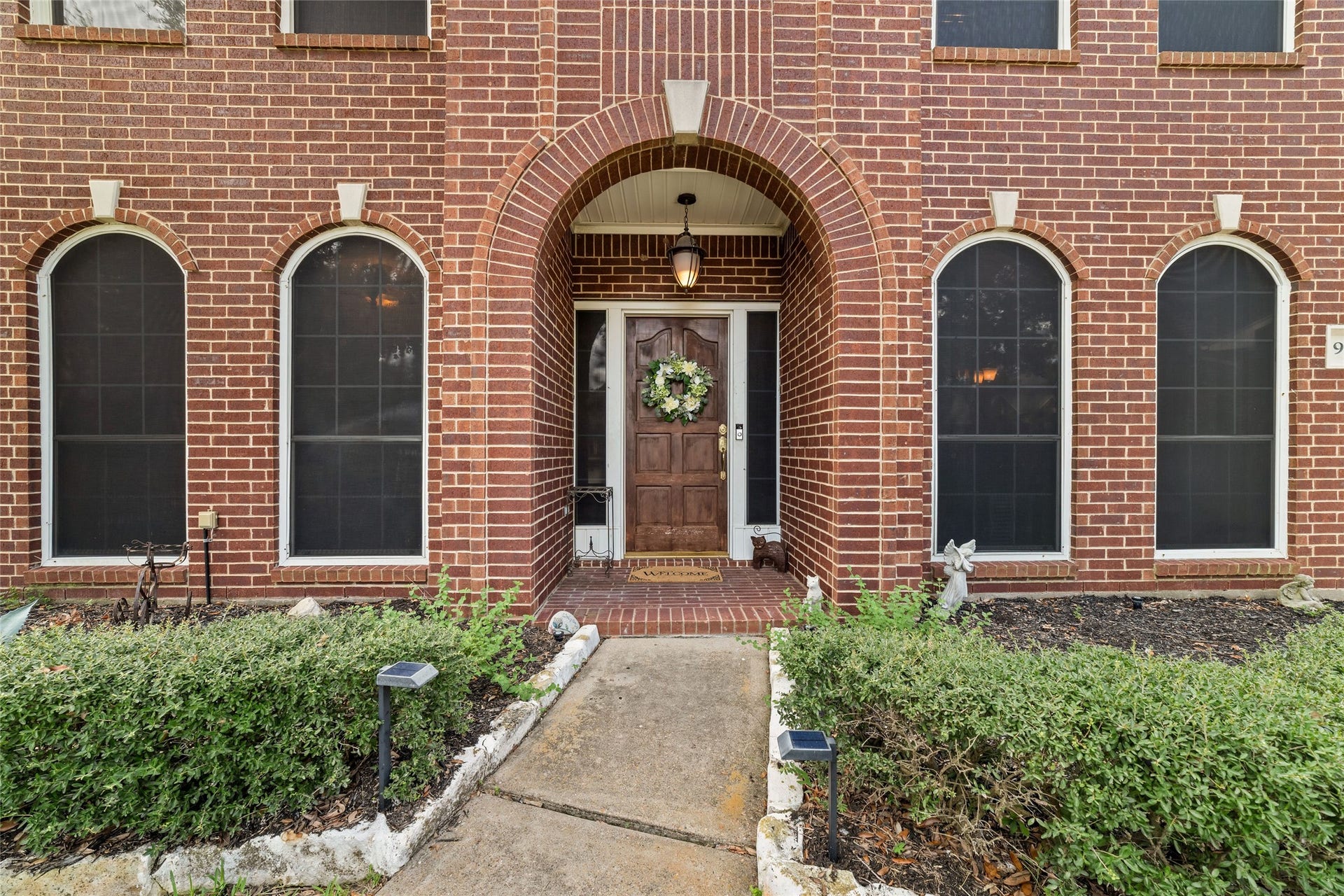 Covered front entry framed by brick arches and tall arched windows.