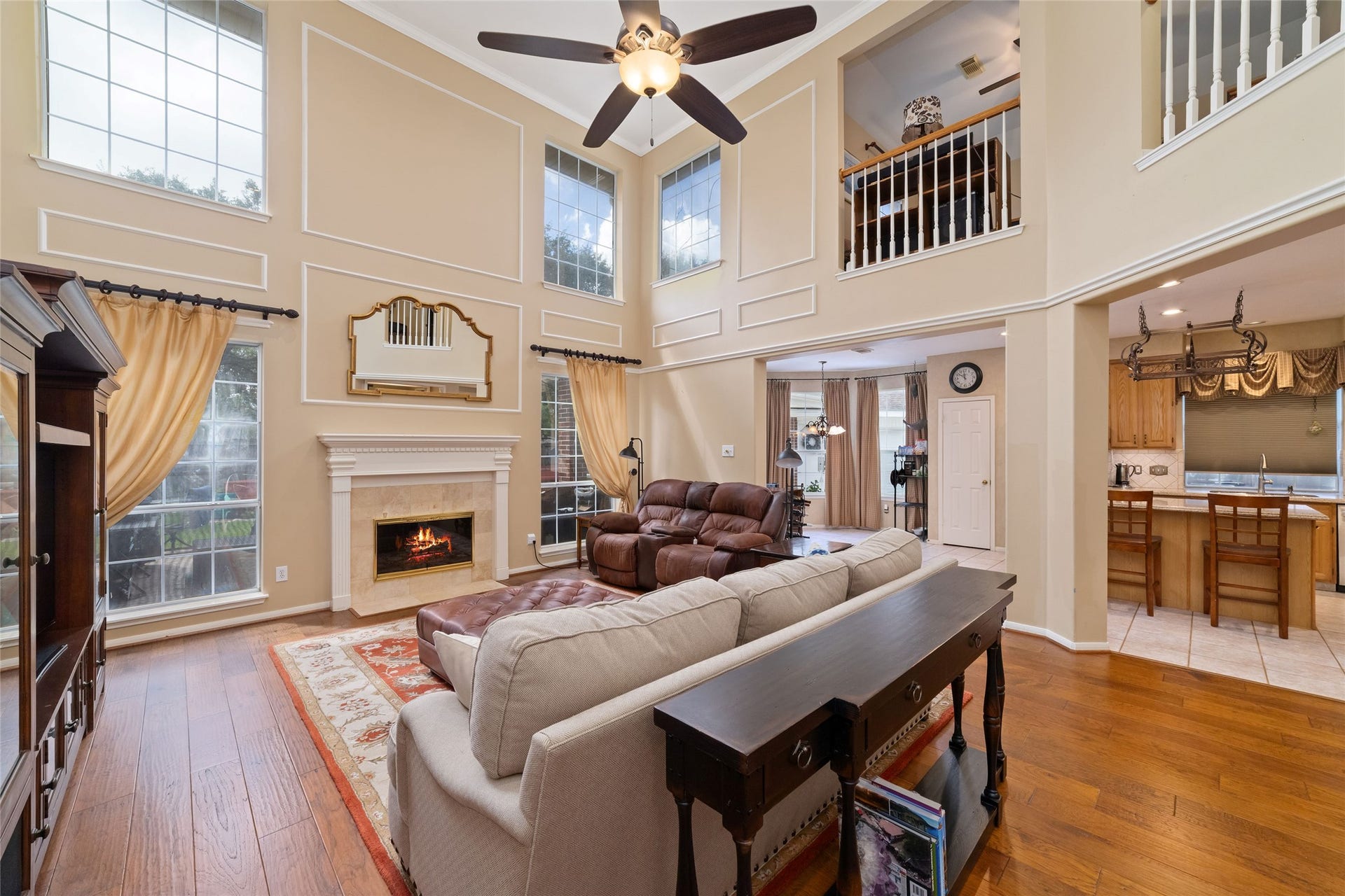 Open living area with soaring ceilings, abundant natural light, fireplace, and direct connection to the kitchen.
