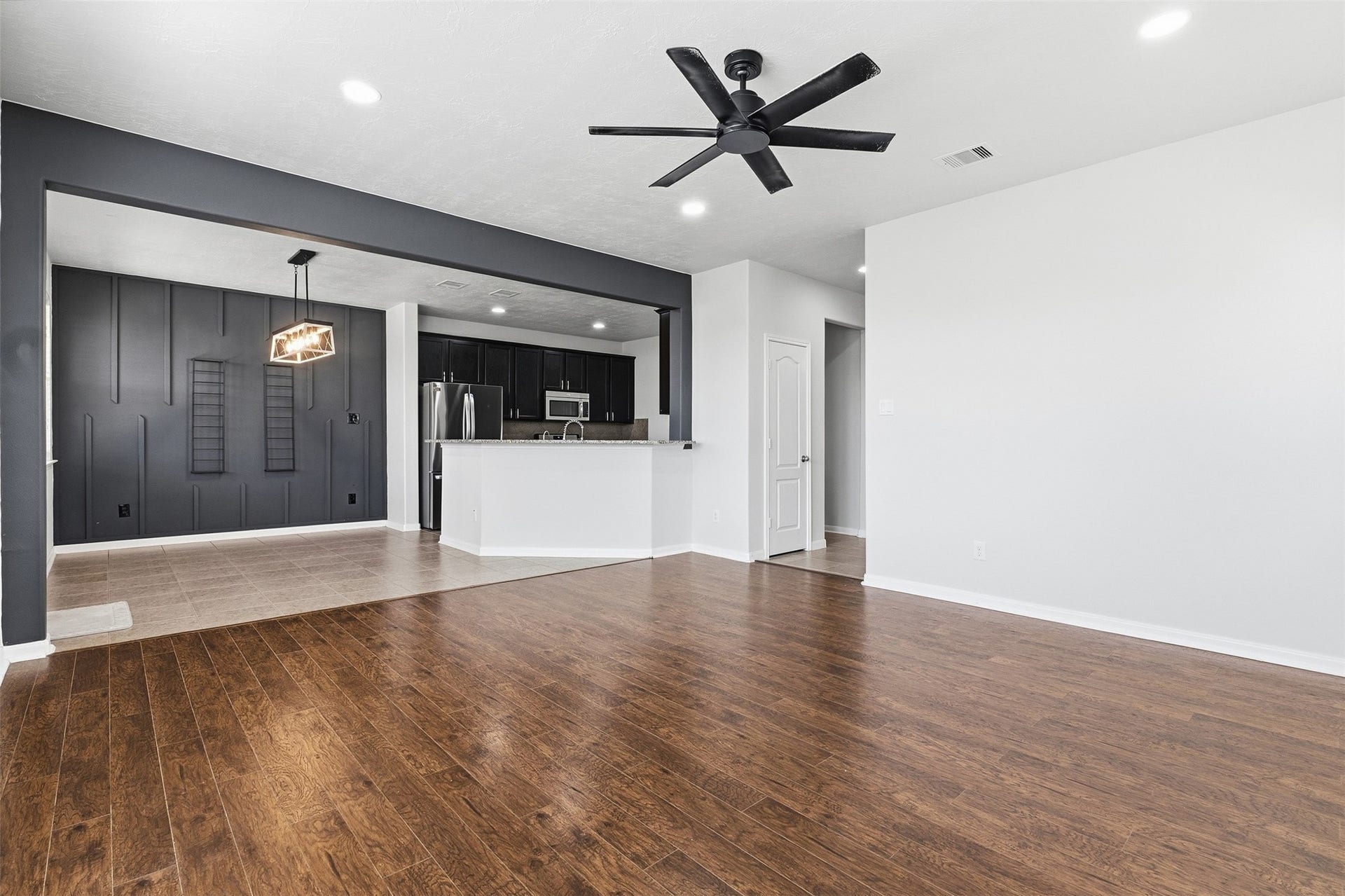 Spacious open-concept living area featuring wood-look flooring, recessed lighting, and a modern ceiling fan.
