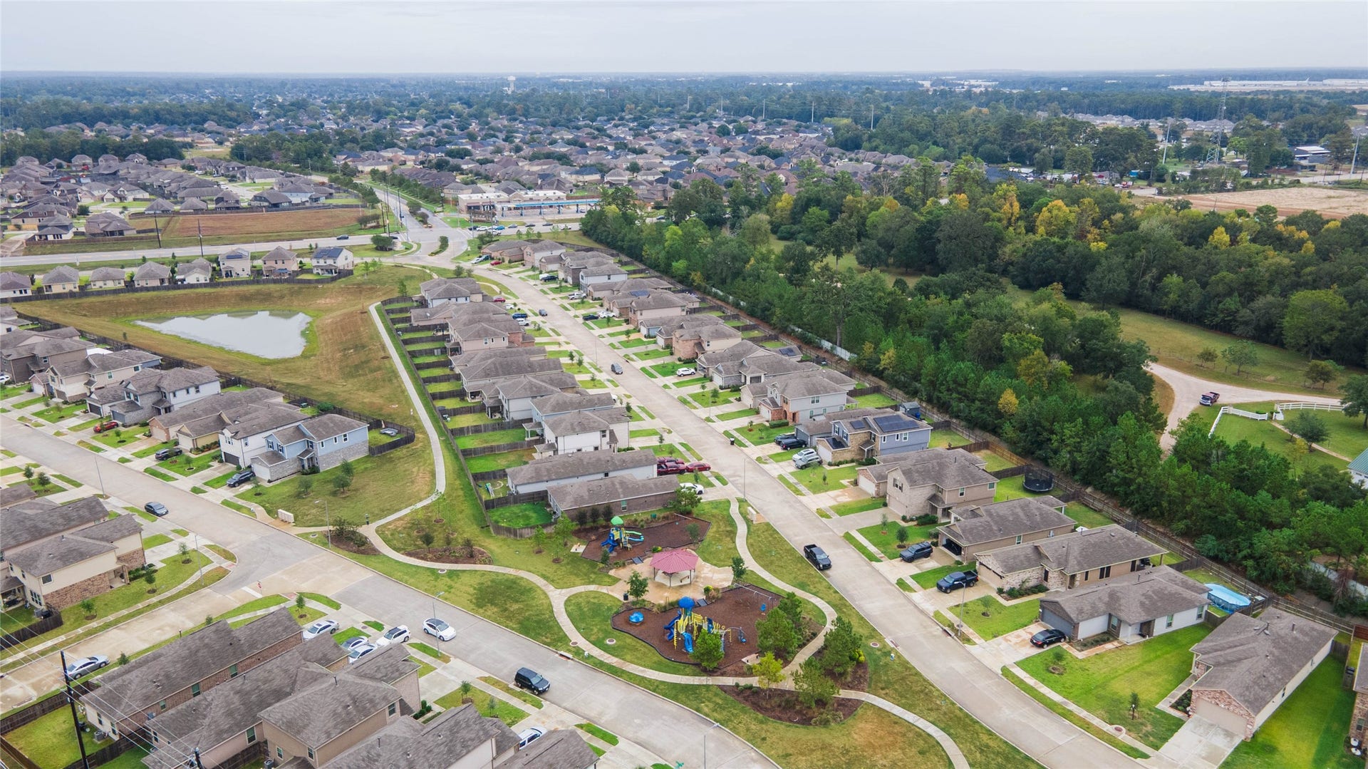 6131 Morning Fern Lane, Humble, TX 77338 This elevated view showcases attractive residential streets framed by a beautiful backdrop of mature trees, offering a peaceful atmosphere with community recreational spaces nearby.