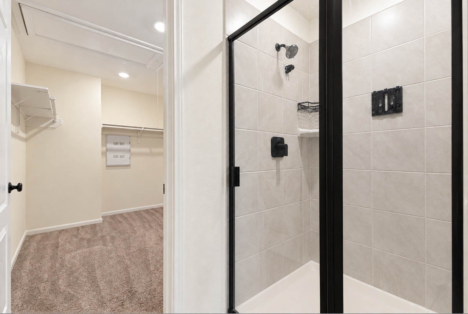6131 Morning Fern Lane, Humble, TX 77338 The spacious walk-in shower showcases beautiful coordinating tilework, a sleek black-framed glass enclosure, & convenient corner shelving, adding both style & functionality to the primary bath.