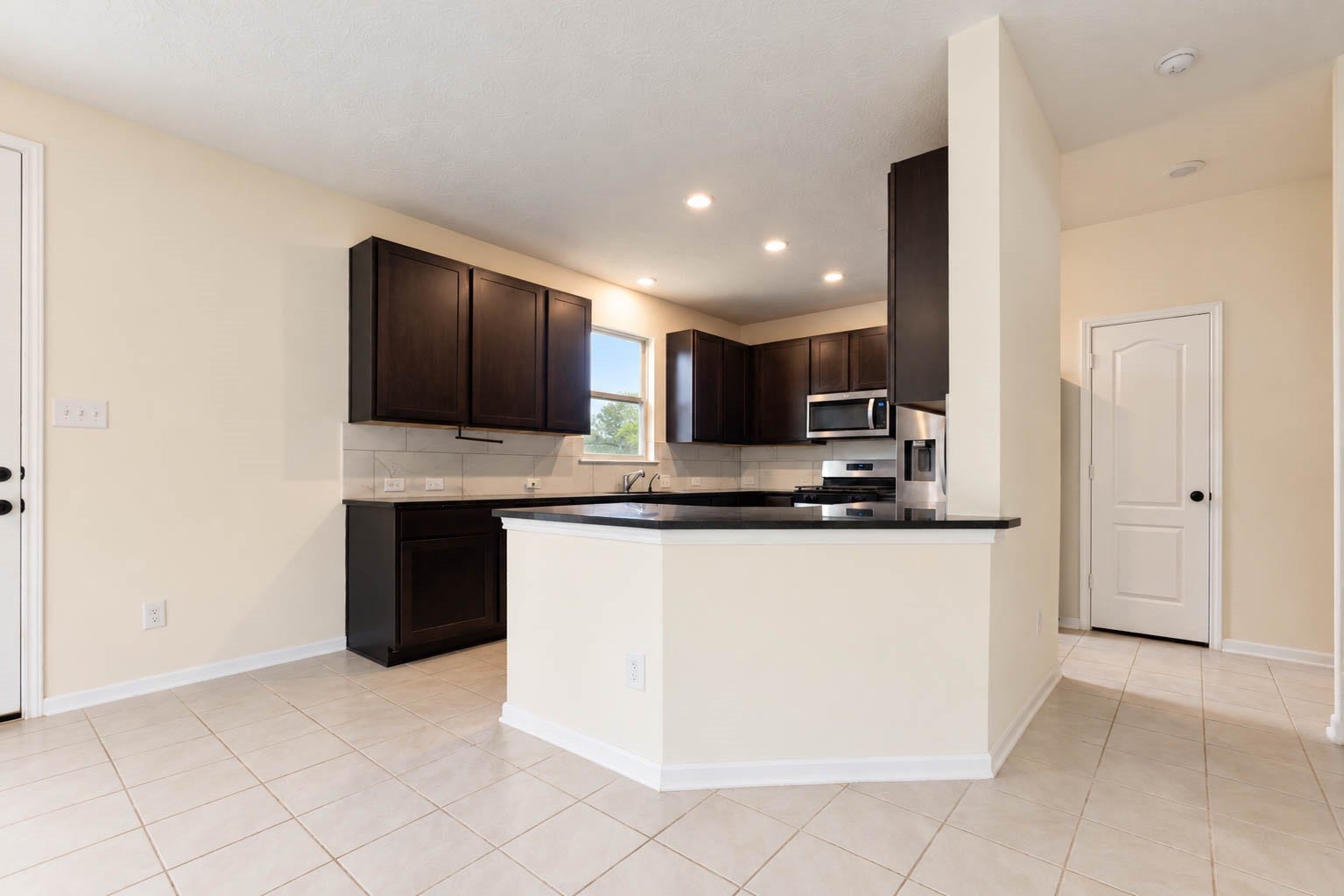 6131 Morning Fern Lane, Humble, TX 77338 Rich espresso-toned cabinetry brings warmth & sophistication to the kitchen, while a spacious breakfast bar provides additional seating for casual dining. A nearby door offers convenient access to the covered patio & backyard, creating an effortless transition to outdoor living.