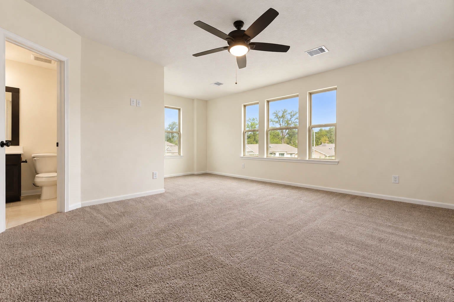 6131 Morning Fern Lane, Humble, TX 77338 Plush carpeting, a soothing neutral color palette, & a stylish ceiling fan enhance the room's warmth & comfort, while multiple windows fill the space with abundant natural light, creating a bright & relaxing retreat.