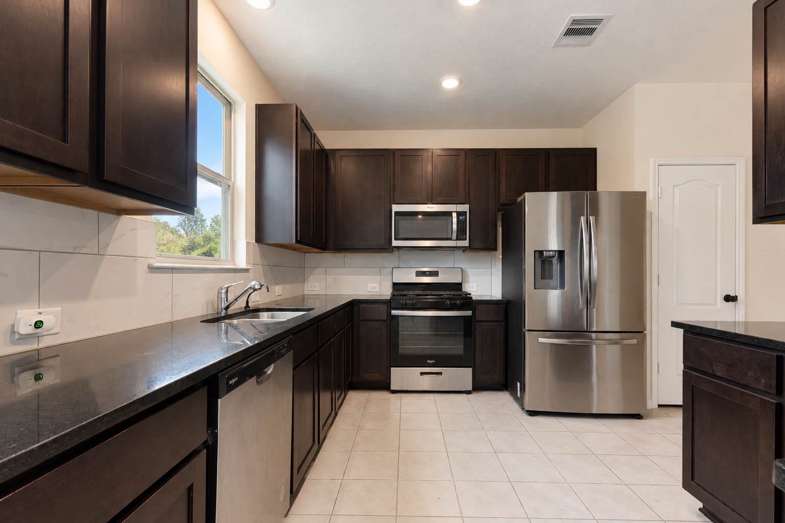 6131 Morning Fern Lane, Humble, TX 77338 The beautifully appointed kitchen showcases sleek granite countertops, a stylish tile backsplash, & abundant cabinetry, complemented by generous counter space & a convenient pantry for exceptional storage & everyday functionality.