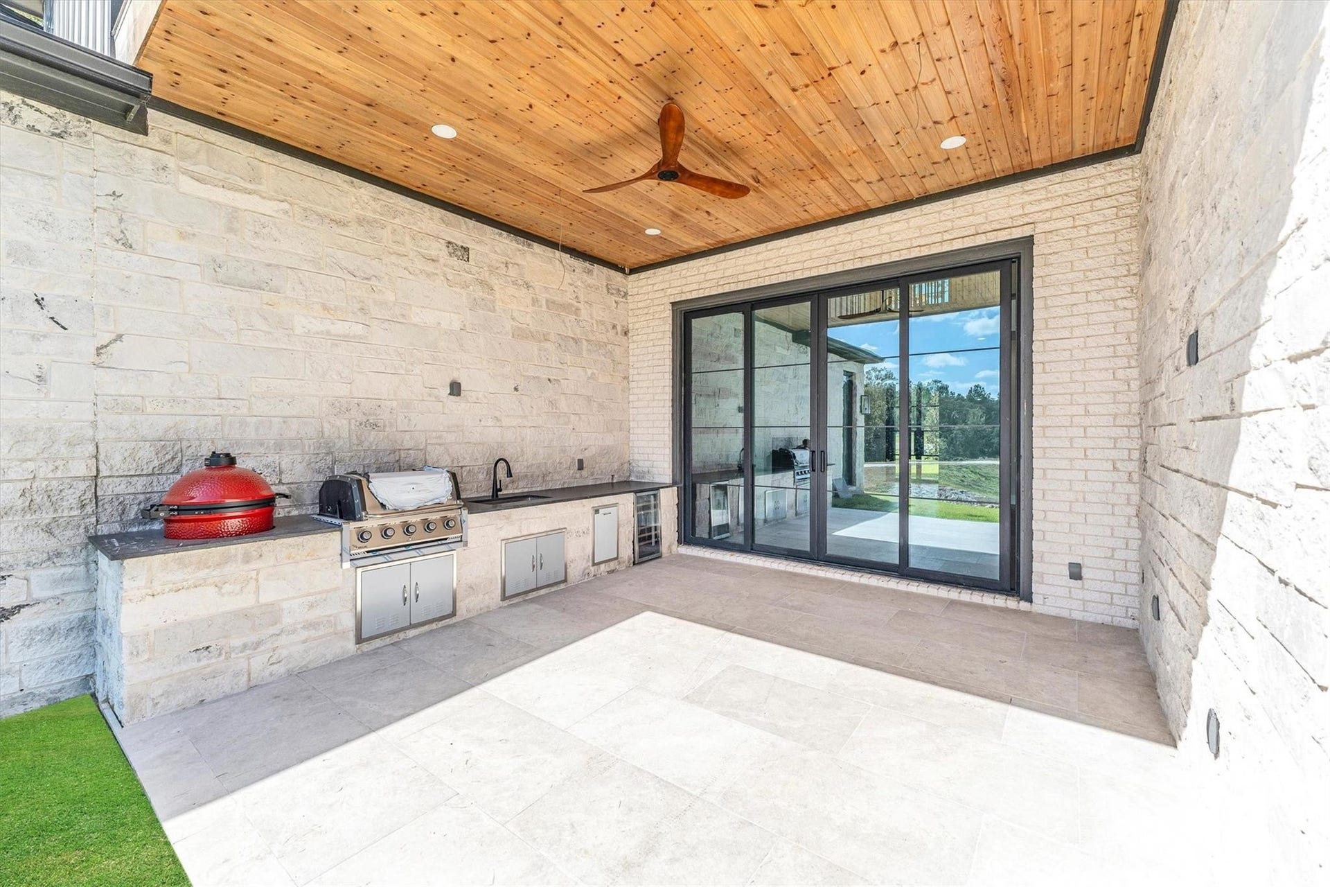 23701 Birch Grove Road, Montgomery, TX 77316 Experience outdoor entertaining at its finest with a complete kitchen featuring a conventional grill, stone grill, fridge, sink, and extended countertop, all set against a backdrop of elegant stonework.