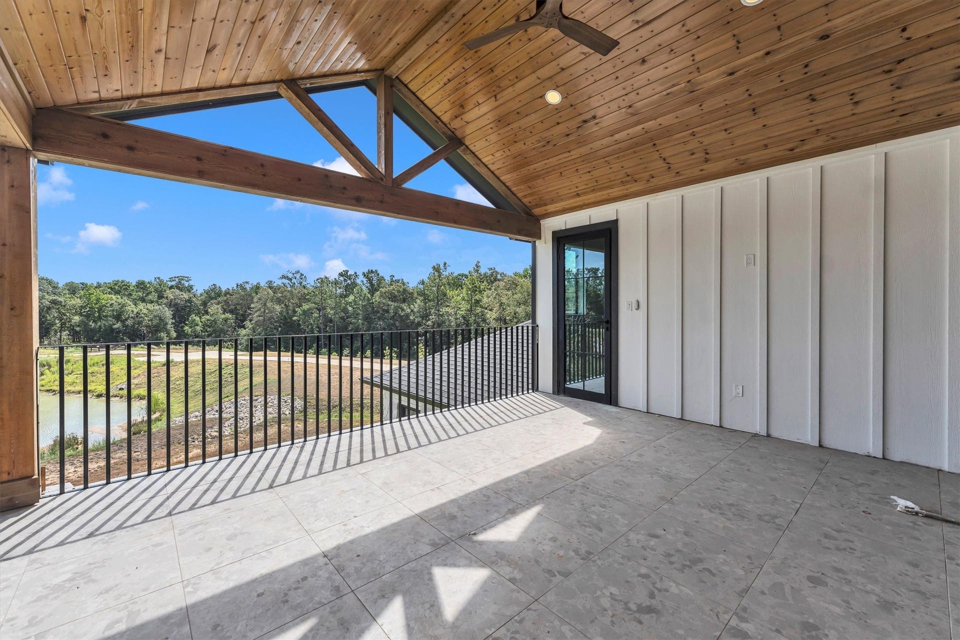 23701 Birch Grove Road, Montgomery, TX 77316 Stunning covered balcony with a vaulted wood ceiling and expansive views of lush greenery, perfect for relaxation or entertaining.