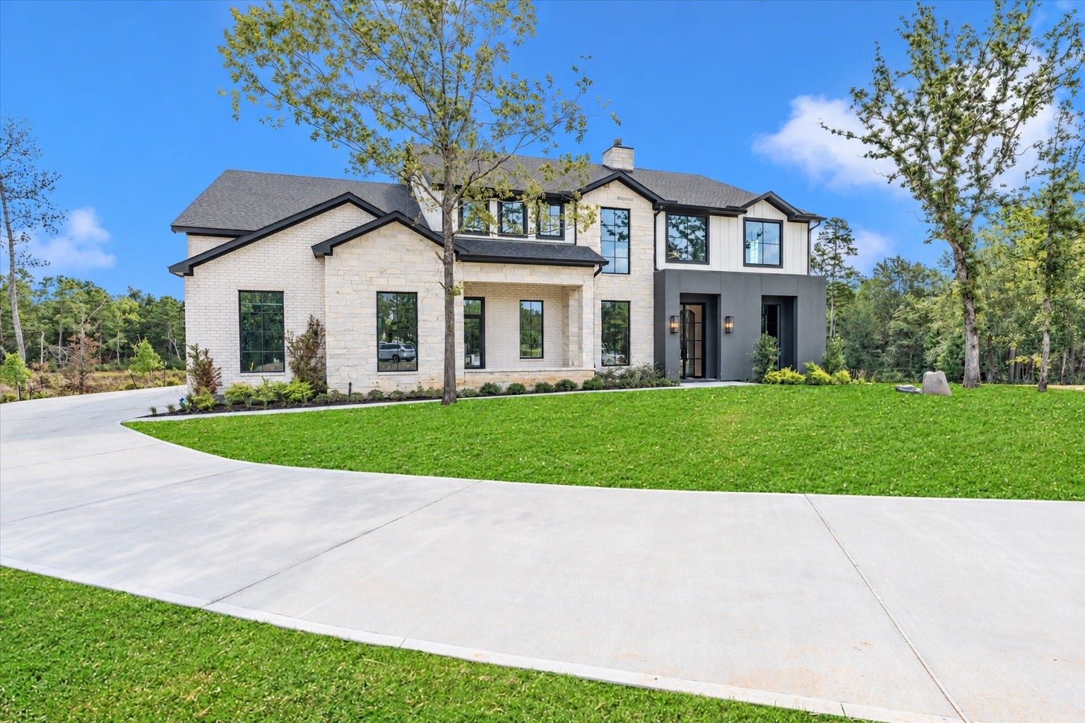 23701 Birch Grove Road, Montgomery, TX 77316 Stunning modern facade with elegant brickwork and expansive windows, set amidst lush greenery on a spacious, inviting lot.