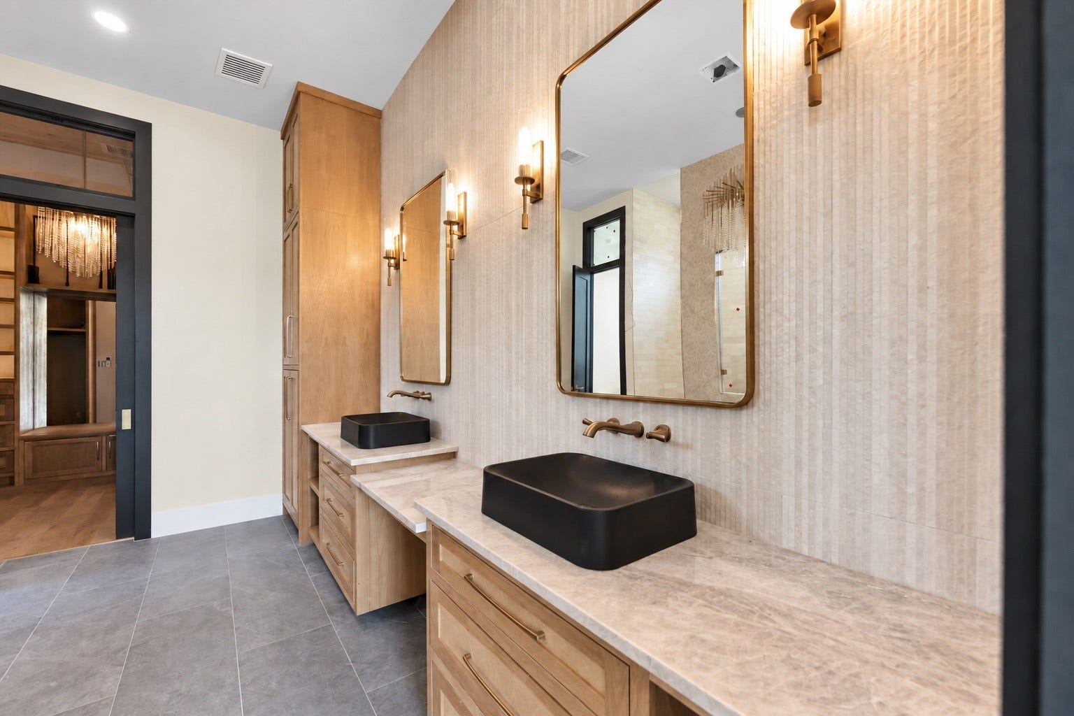 23701 Birch Grove Road, Montgomery, TX 77316 Elegant bathroom featuring dual vanities with sleek black vessel sinks, framed mirrors, and warm wood cabinetry, complemented by stylish wall sconces.