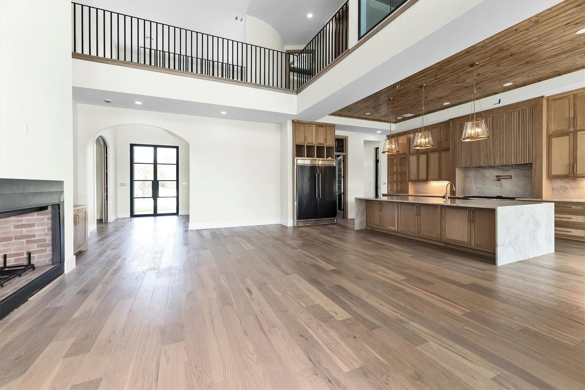 23701 Birch Grove Road, Montgomery, TX 77316 Discover a spacious open-concept living area featuring elegant hardwood floors, a modern fireplace, and a sleek kitchen with a large island and pendant lighting. The high ceilings and balcony add a touch of grandeur.