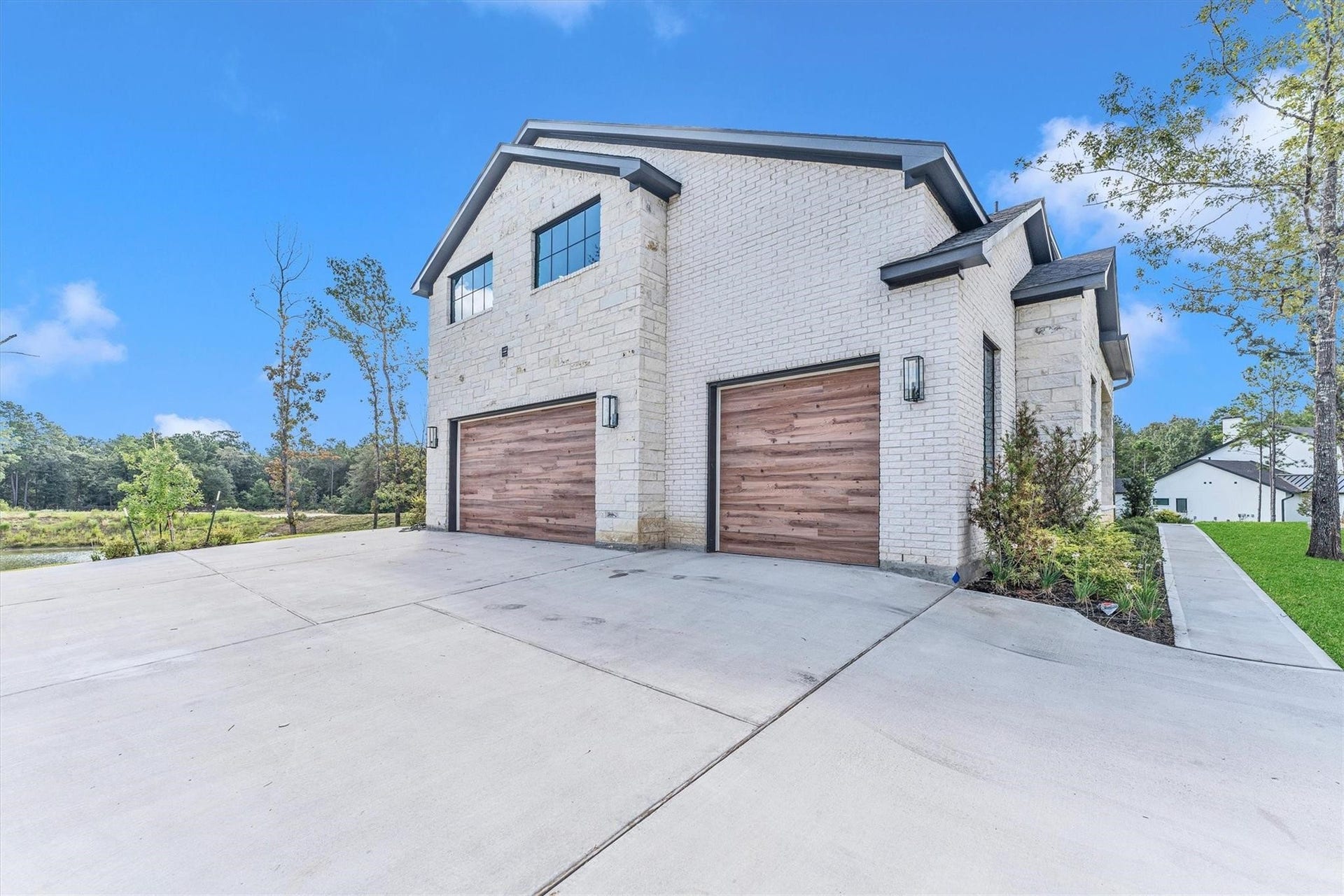 23701 Birch Grove Road, Montgomery, TX 77316 Stunning modern home with a spacious three-car garage, offering ample parking and storage in a serene, picturesque setting.