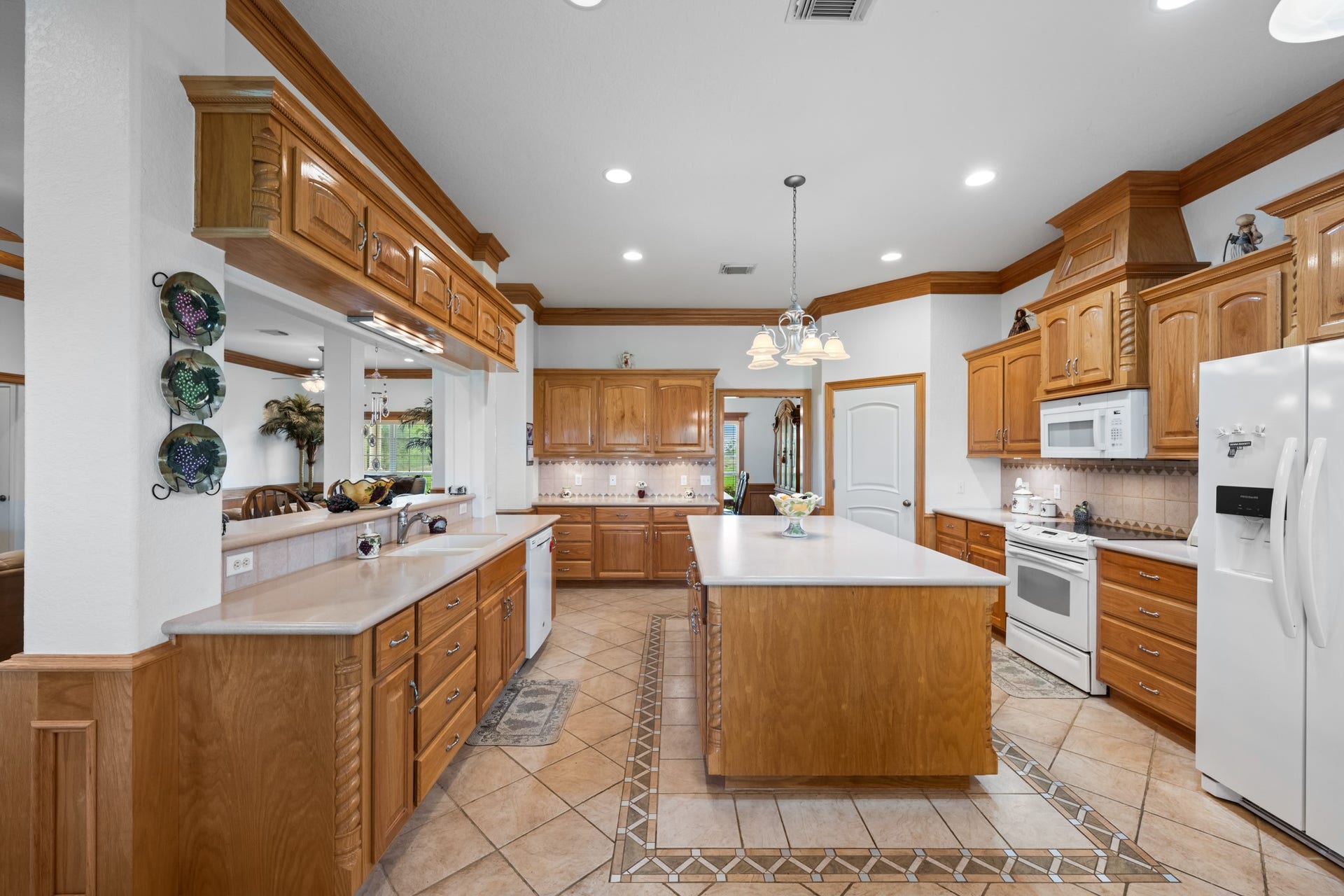 Spacious kitchen featuring beautiful custom wood cabinetry, detailed crown molding, a large center island, abundant counter space, and an open layout perfect for everyday living and entertaining