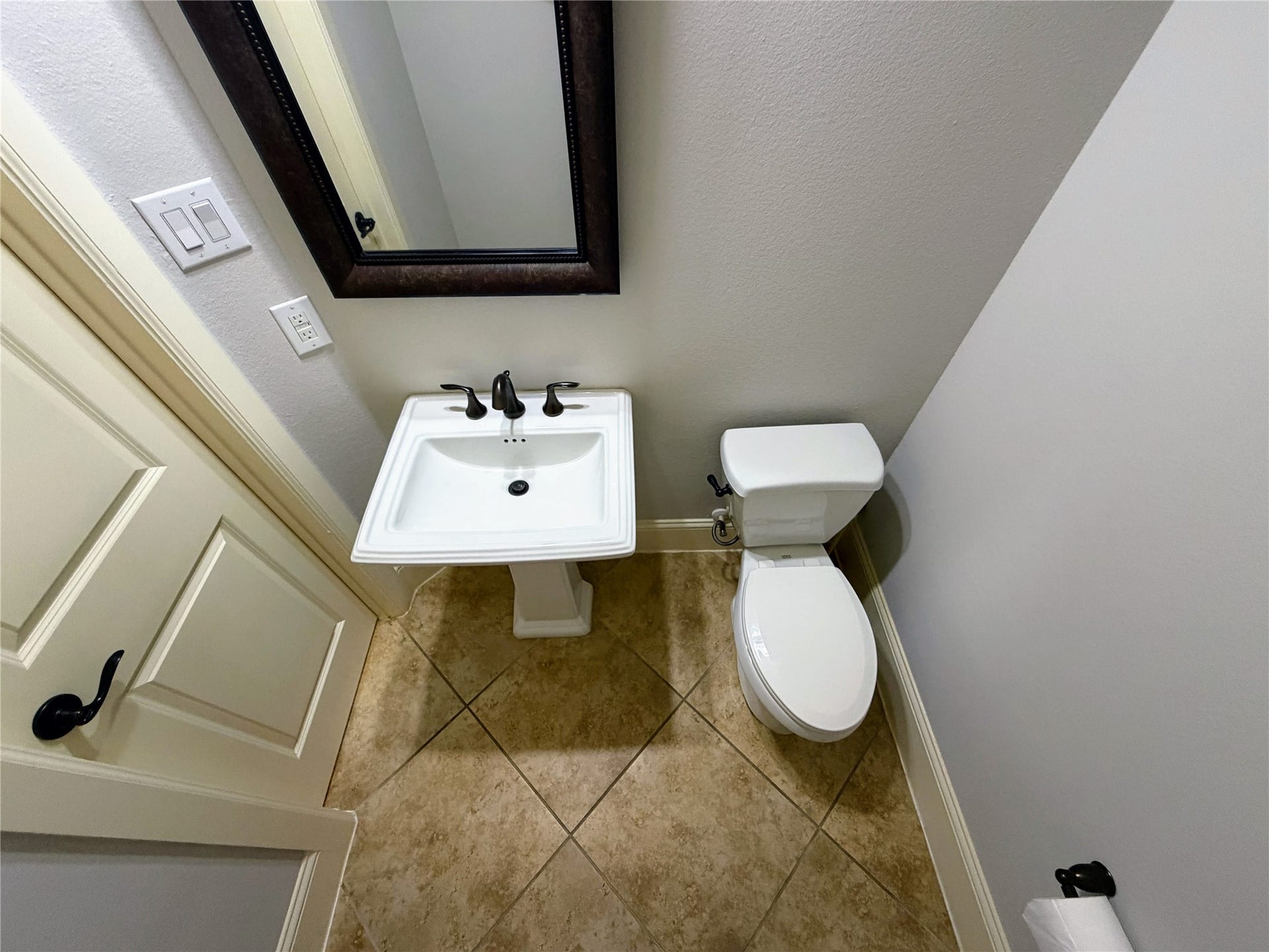 5119 Water Oak Crescent, Fulshear, TX 77441 Conveniently located powder room perfect for guests! Features a classic porcelain pedestal sink, elegant oil-rubbed bronze fixtures, a framed mirror, and durable tile flooring.