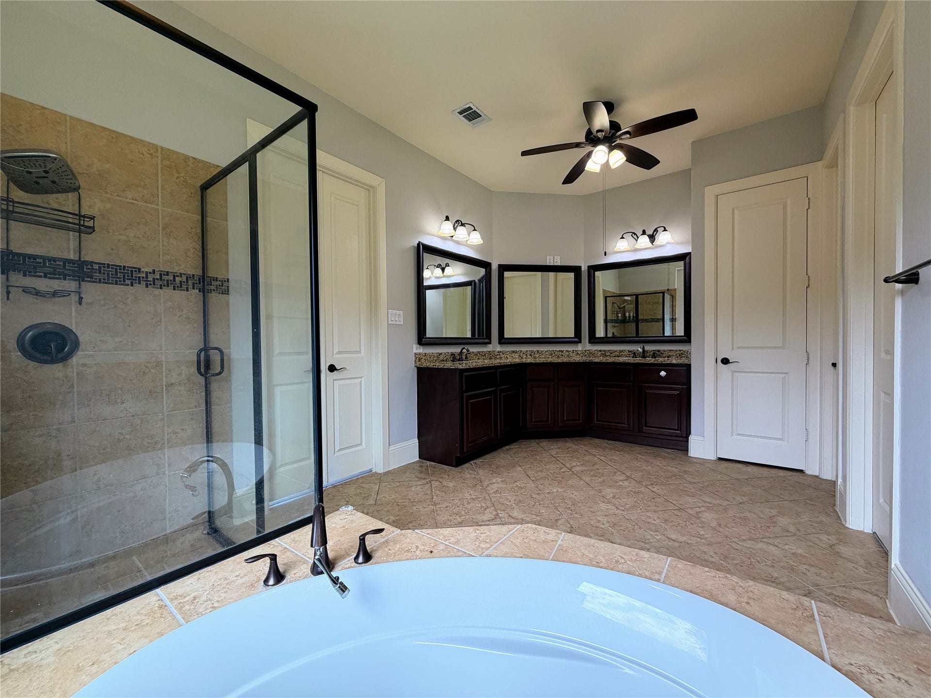 5119 Water Oak Crescent, Fulshear, TX 77441 Luxurious primary bath oasis! Features a deep soaking tub, a separate glass-enclosed walk-in shower, elegant tile details, and a bright window.