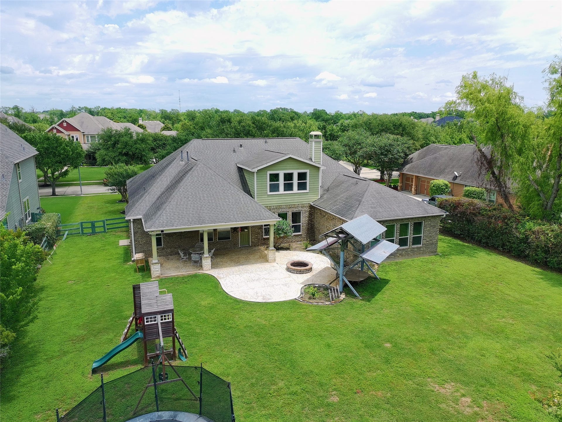 5119 Water Oak Crescent, Fulshear, TX 77441 Spectacular aerial view of the massive backyard! Showcases the expansive covered patio, large stamped concrete terrace with a fire pit, standalone pavilion, and an incredible amount of lush green lawn.