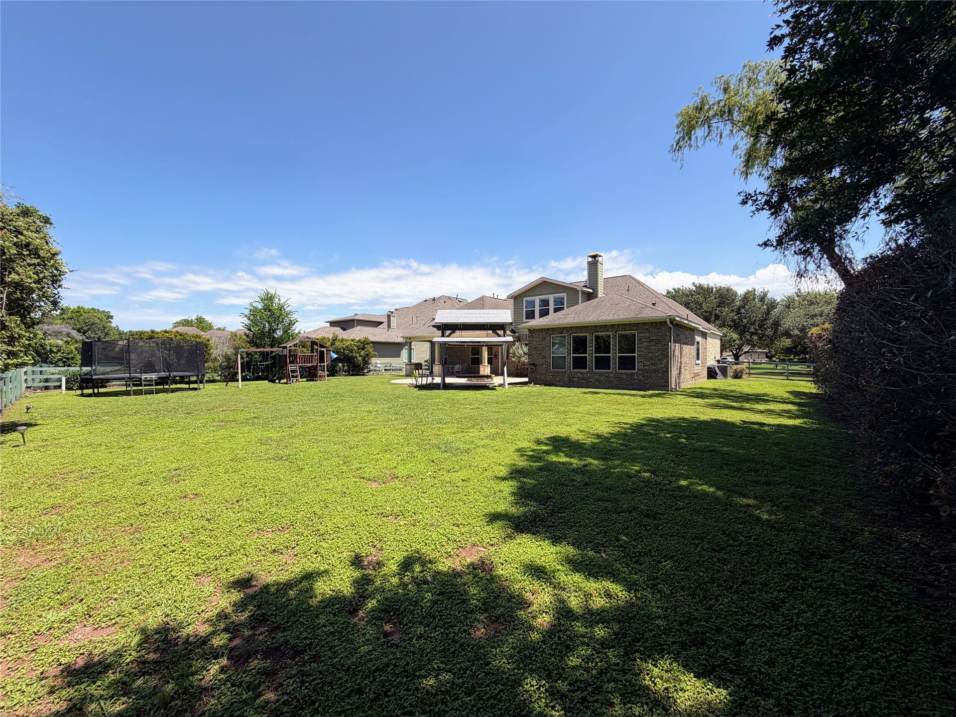 5119 Water Oak Crescent, Fulshear, TX 77441 Massive, fully fenced backyard oasis! Boasts a sprawling green lawn, mature trees for shade, a covered patio with an open pavilion, and endless space for a pool, playscape, or outdoor entertaining.