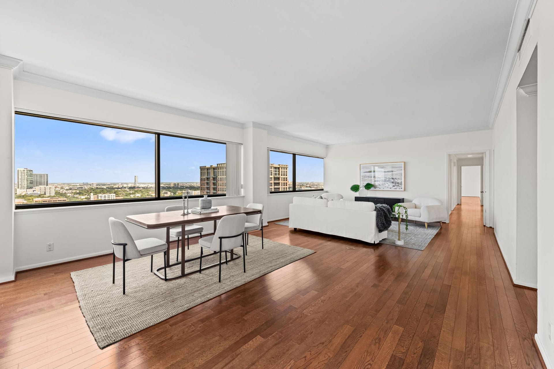 This perspective showcases the residence's broad entertaining spaces and uninterrupted flow. Warm hardwood flooring unifies the living and dining areas with timeless appeal. Panoramic views from every room & two private balconies overlooking the city.