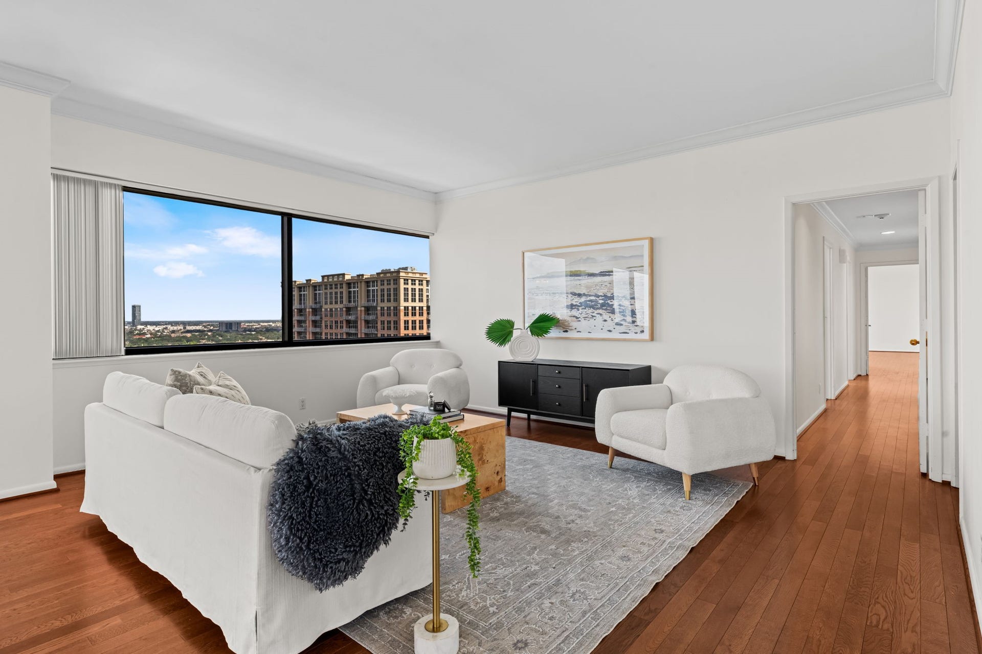 Panoramic windows wrap the living space in natural light while highlighting Houston's expansive skyline. The spacious floor plan provides flexibility for multiple conversation and activity zones.