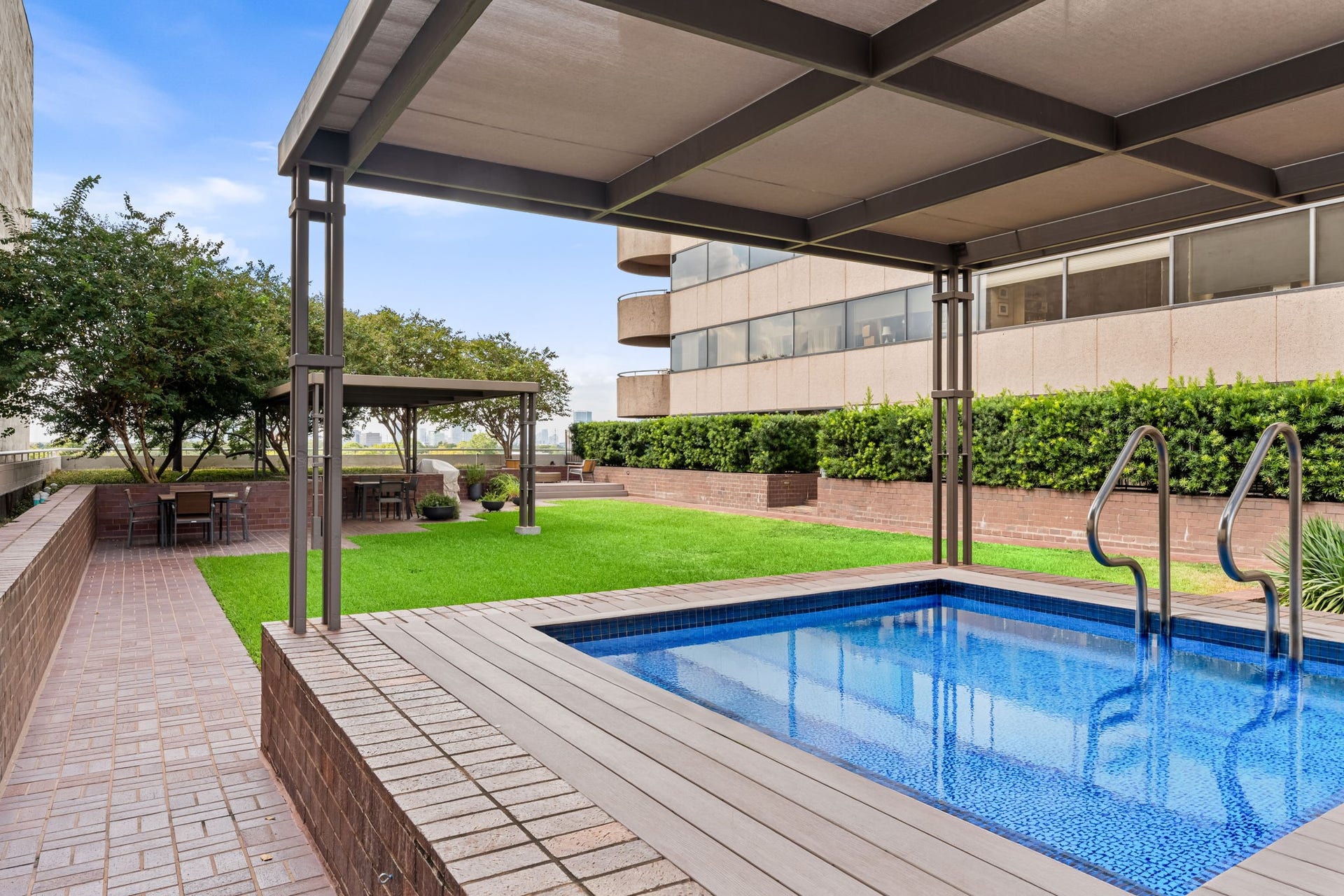 A covered poolside area provides shade beside the building's outdoor swimming pool. The thoughtful arrangement supports comfortable enjoyment of the sixth-floor recreational level.