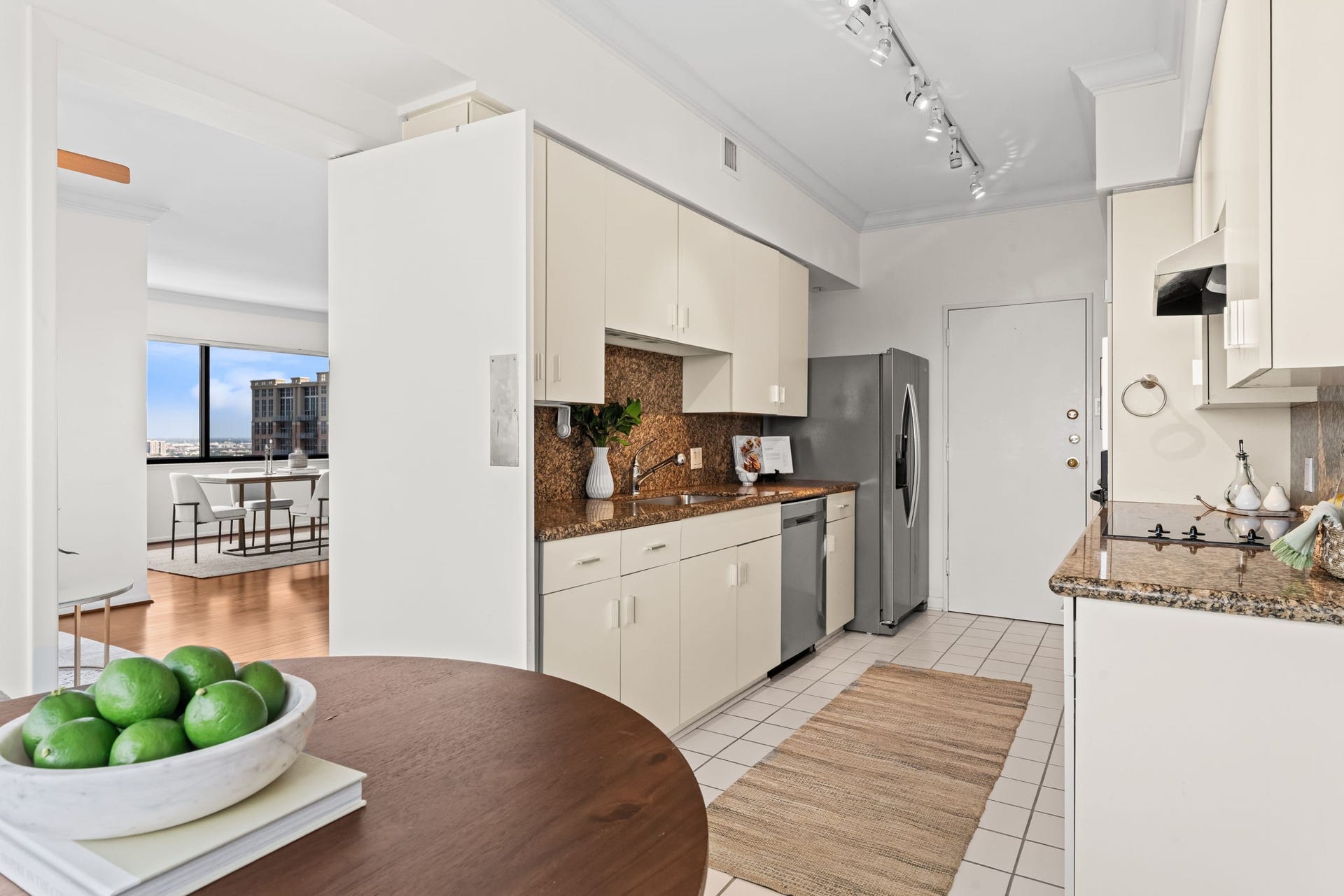 The kitchen is thoughtfully positioned near both formal and casual dining spaces. A light, neutral finish keeps the room bright and complements the surrounding hardwood floors.