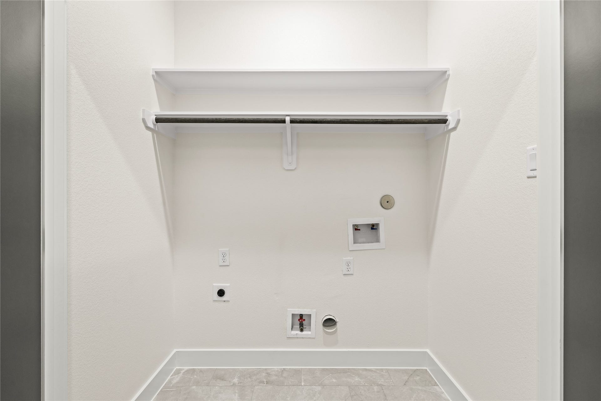 4521 Newberry Street, Houston, TX 77051 Dedicated laundry space built-in overhead shelf and hanging rod set over grey tile flooring.