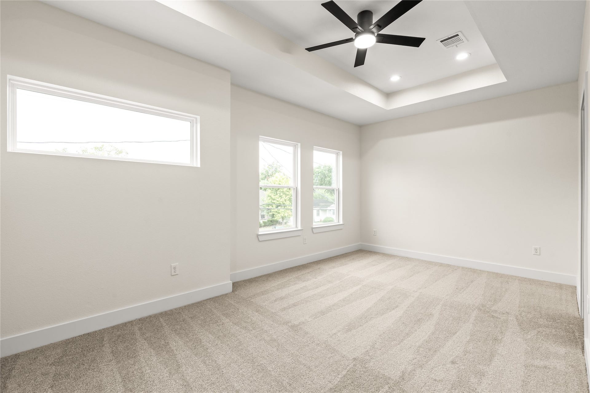 4521 Newberry Street, Houston, TX 77051 Primary bedroom retreat tray ceiling with recessed lighting, black ceiling fan, transom accent window, and wall-to-wall plush carpet.