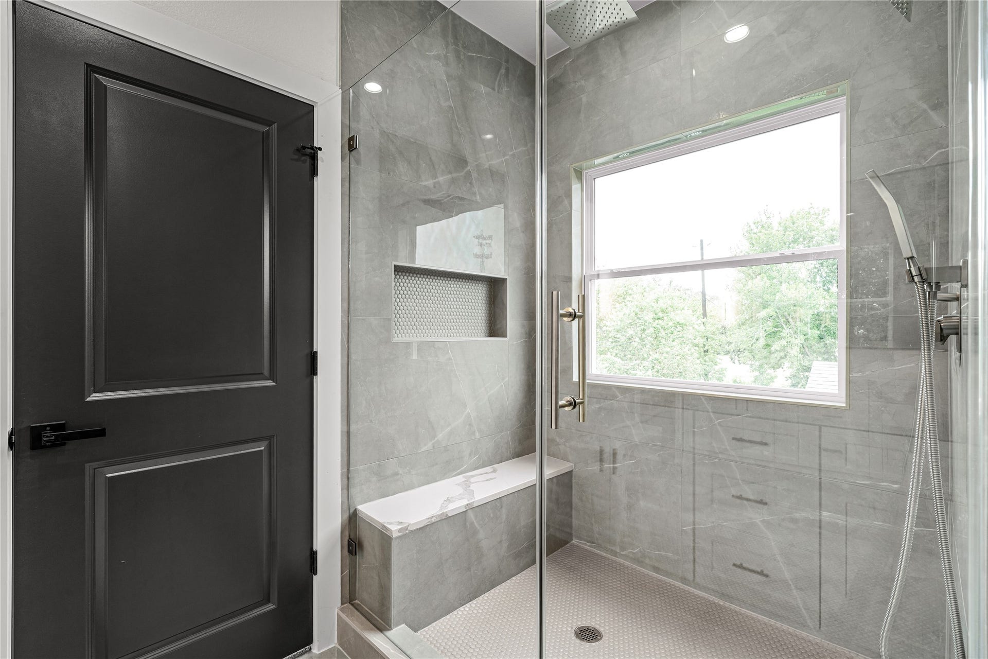 4521 Newberry Street, Houston, TX 77051 Light-filled shower nook oversized window streaming natural light, built-in mosaic niche, and sleek modern fixtures.