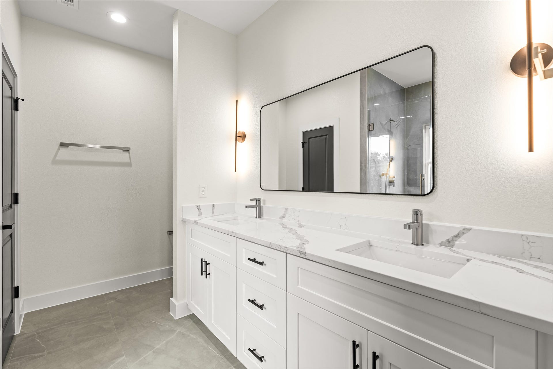 4521 Newberry Street, Houston, TX 77051 Primary bathroom vanity white quartz countertops with delicate gray veining, double under-mount sinks, sleek black hardware, and designer sconce lighting.