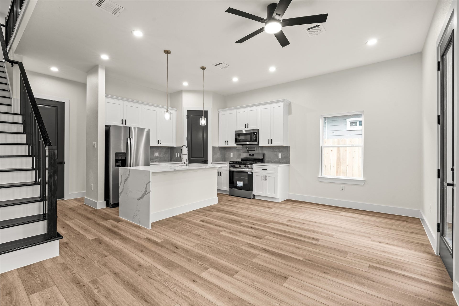 4521 Newberry Street, Houston, TX 77051 Generous main-level entertaining space flooded with natural light from large picture windows, framed by wrought-iron staircase detailing.