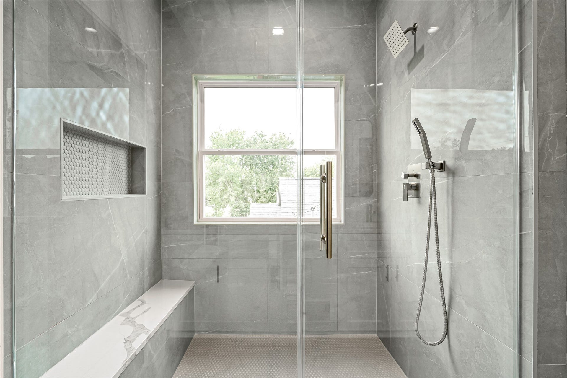 4521 Newberry Street, Houston, TX 77051 Primary walk-in shower floor-to-ceiling slate gray tile, frameless glass enclosure, built-in quartz bench, and rainfall showerhead with handheld sprayer.