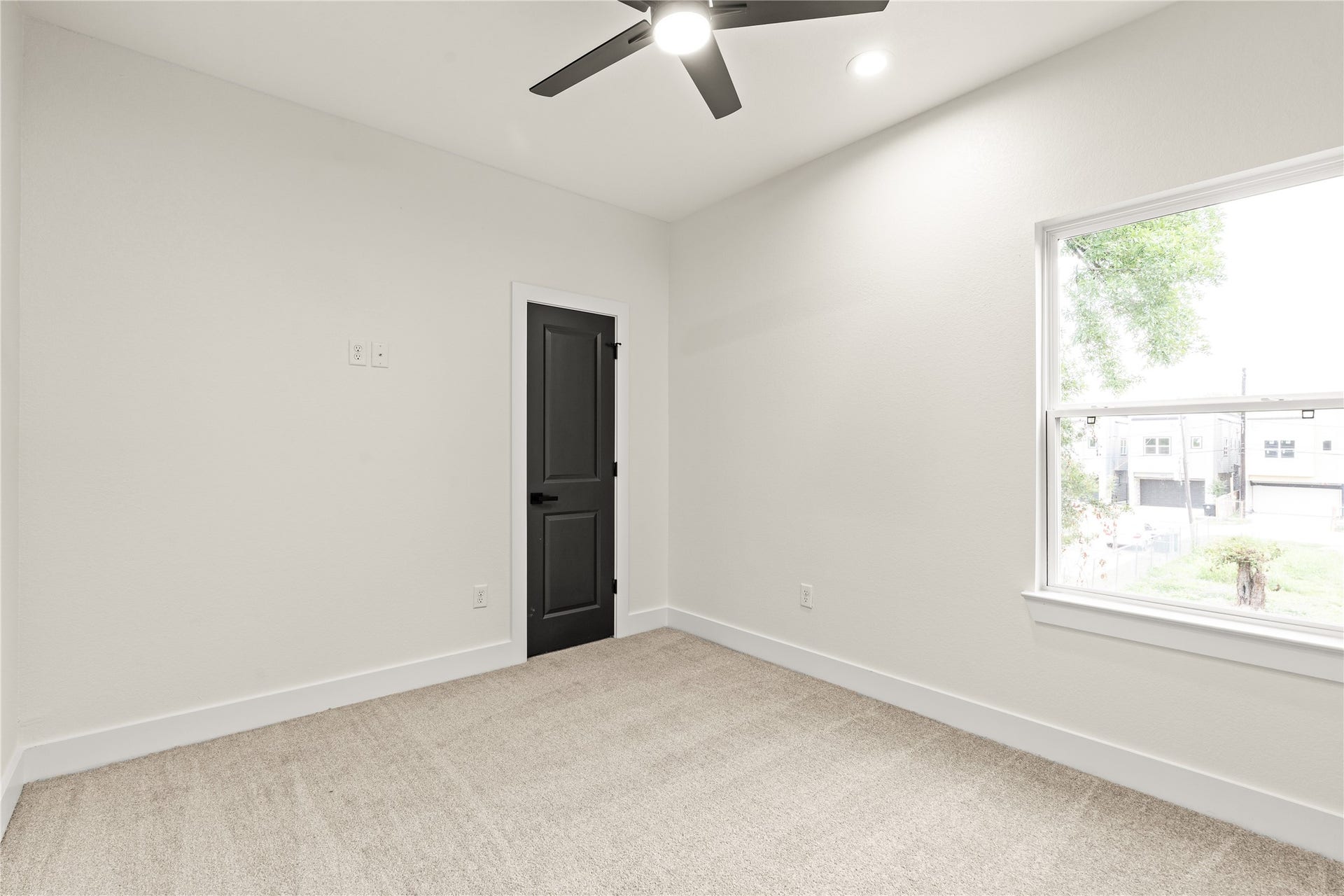4521 Newberry Street, Houston, TX 77051 Sunlit guest bedroom large picture window framing quiet neighborhood views, modern ceiling fan, and soft plush carpeting.