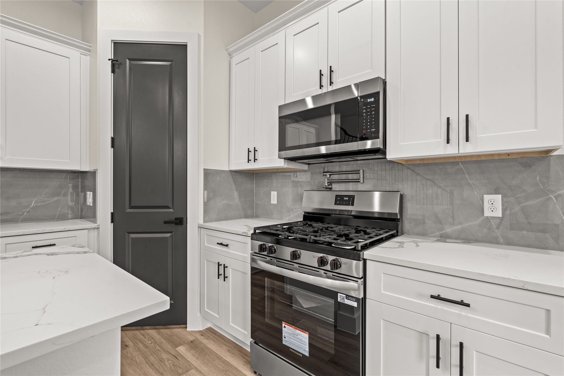 4521 Newberry Street, Houston, TX 77051 Gourmet cooking wall pot filler over the gas range, custom quartz backsplash, microwave drawer, and surrounding shaker cabinetry.