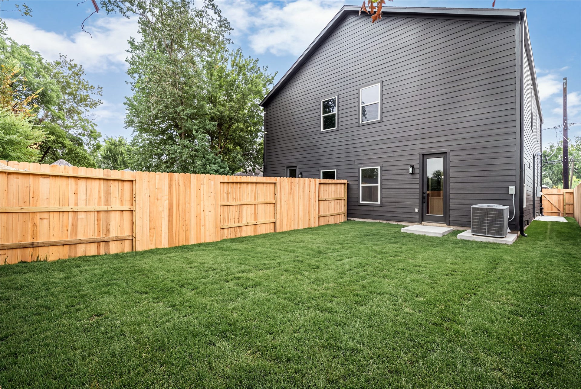 4521 Newberry Street, Houston, TX 77051 Private fully fenced yard expansive lush green lawn, sleek charcoal exterior siding, full glass patio door, and ideal space for weekend gatherings or pets.