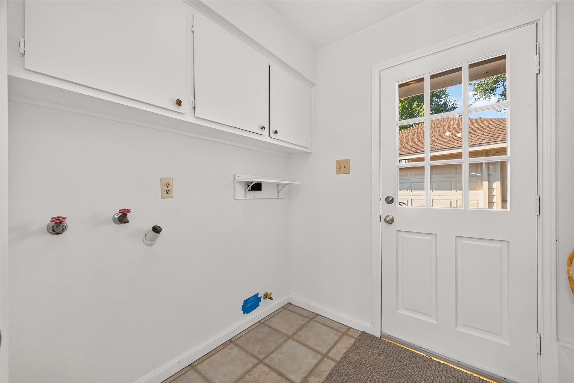 7602 Salge Drive, Houston, TX 77040 Conveniently located laundry room featuring washer and dryer connections, overhead cabinetry for additional storage, and easy-to-maintain tile flooring. A charming glass-paneled exterior door welcomes natural light and provides direct access to the driveway and detached garage.