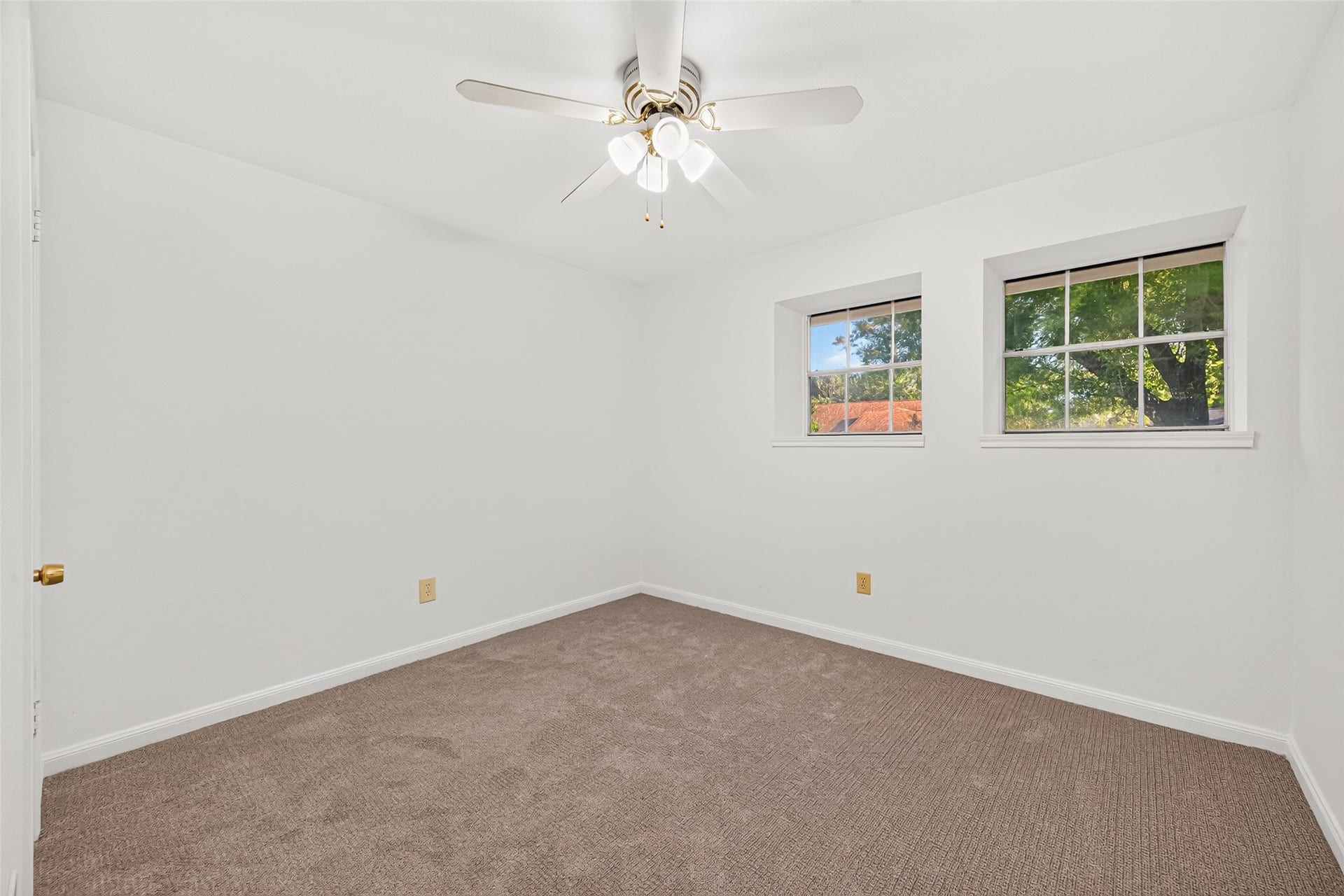 7602 Salge Drive, Houston, TX 77040 Bright and inviting secondary bedroom featuring two charming windows with deep windowsills that add architectural character while offering lovely views of the surrounding greenery. Fresh neutral paint, soft carpeting, and a ceiling fan create a welcoming atmosphere, while a spacious walk-in closet.