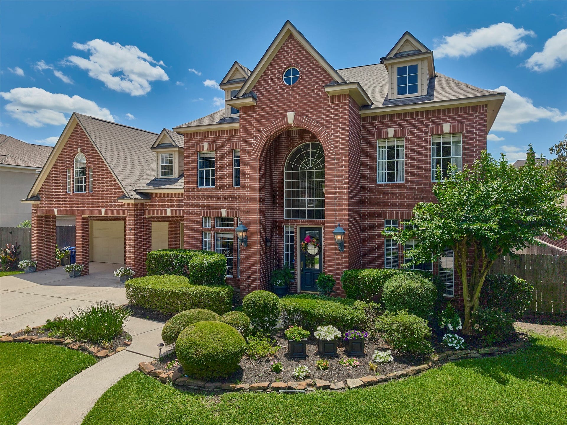 7111 Mohave Hills, Houston, TX 77069 Stunning two-story brick home with elegant arched windows, manicured landscaping, and a spacious driveway leading to a 3-car garage.