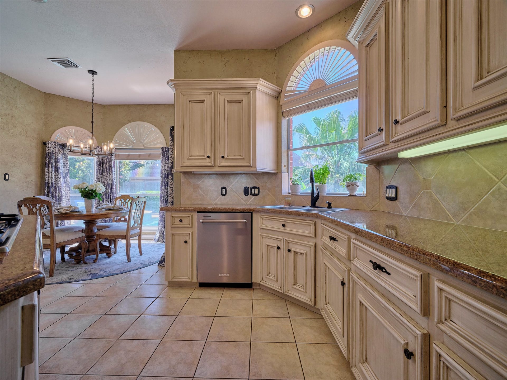7111 Mohave Hills, Houston, TX 77069 Spacious kitchen with elegant cabinetry, granite countertops, and abundant natural light. Adjacent dining area features a charming chandelier and large windows with garden views.