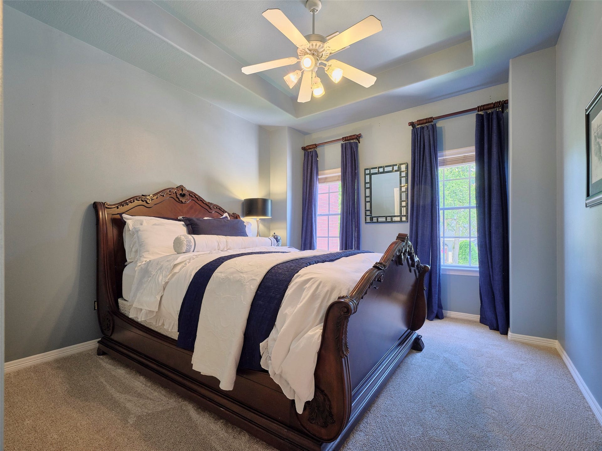 7111 Mohave Hills, Houston, TX 77069 Elegant bedroom featuring a beautifully carved wooden bed, plush carpeting, and large windows with deep blue curtains that invite natural light.