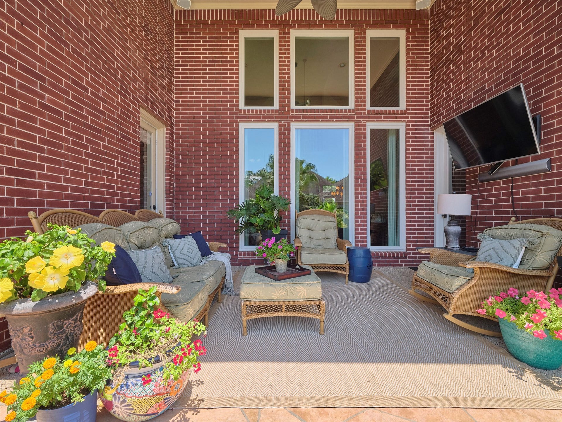 7111 Mohave Hills, Houston, TX 77069 Charming outdoor living space features cozy wicker seating, vibrant potted plants, and large windows overlooking a serene setting, perfect